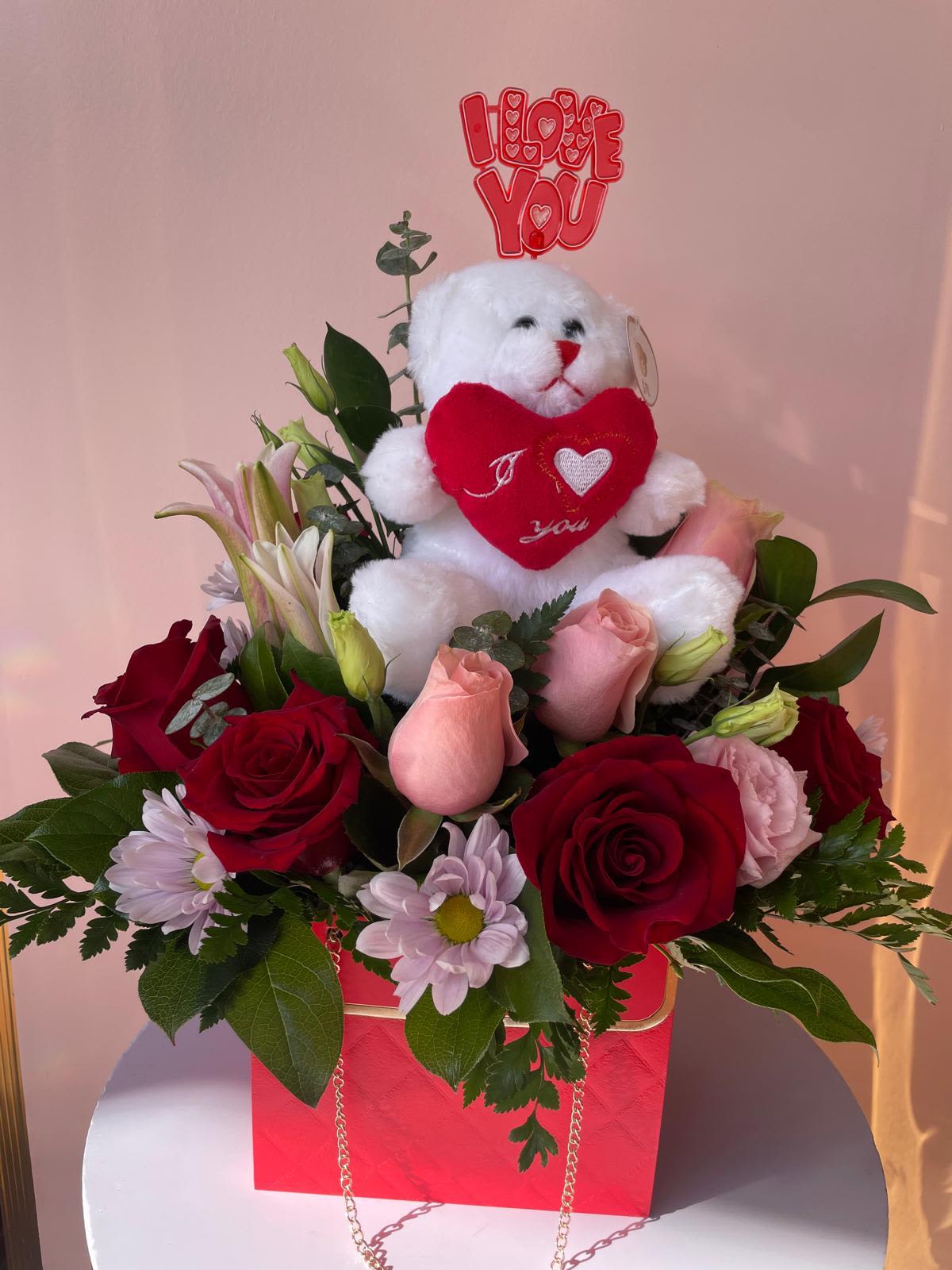 Red roses and pink flowers with a teddy bear holding a heart