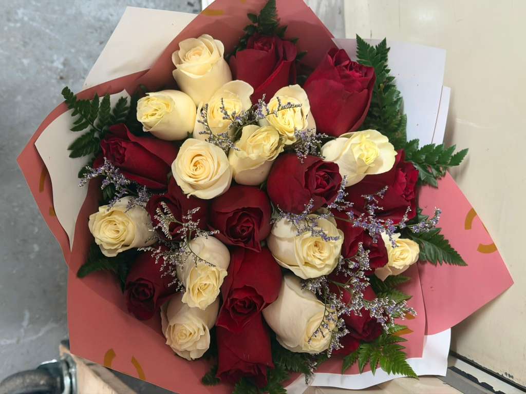 Bouquet of red and cream roses wrapped in pink paper