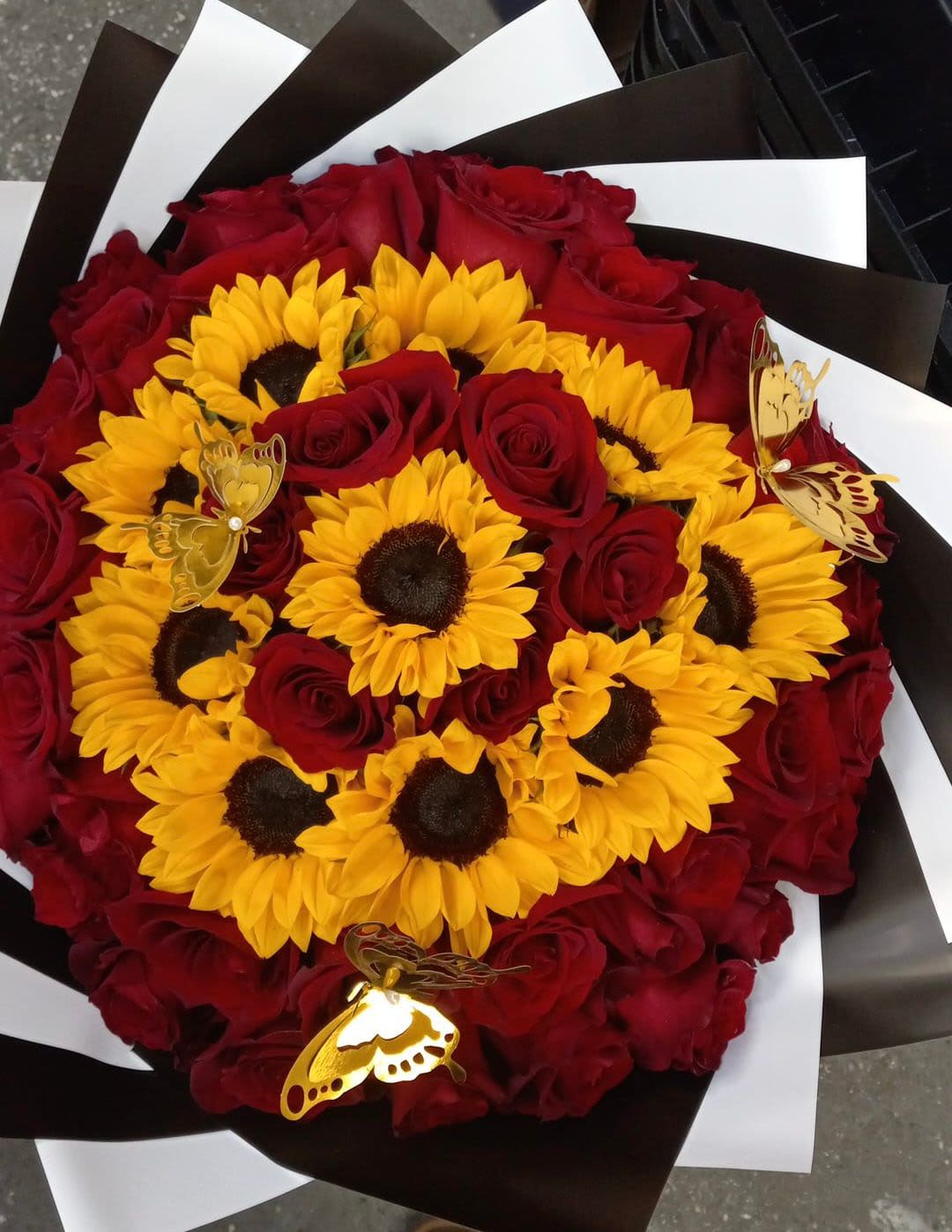 Bouquet of red roses and yellow sunflowers with butterfly picks