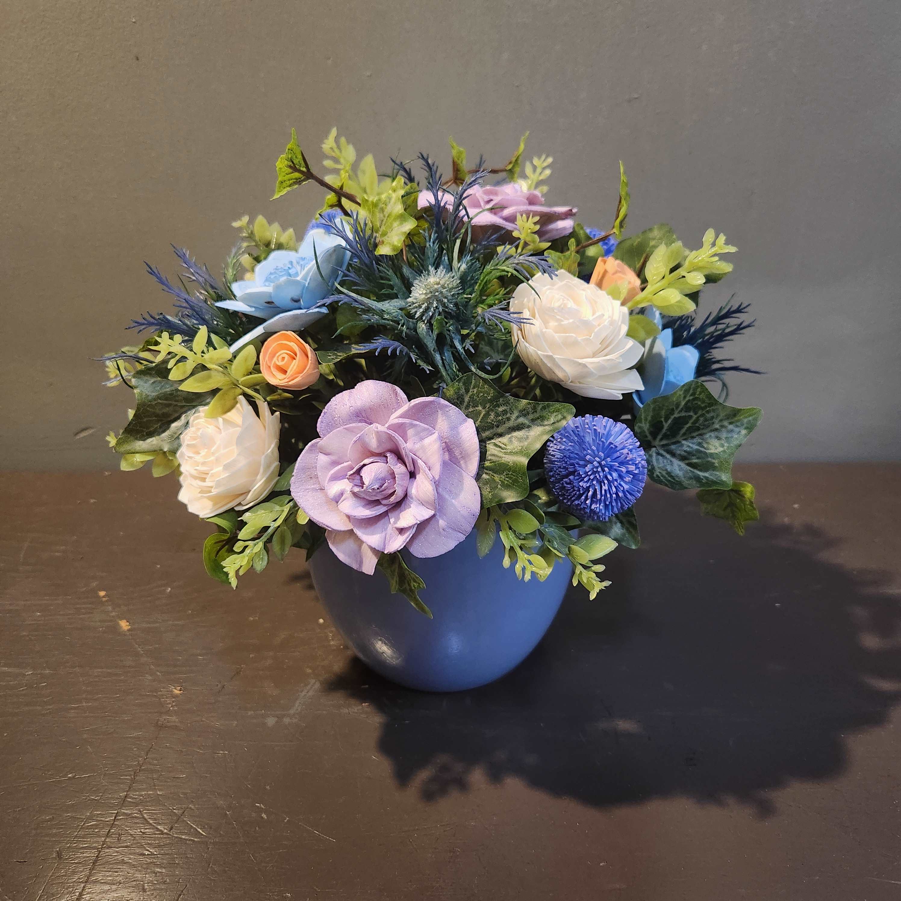 Artificial flower arrangement in a blue pot with pastel blooms