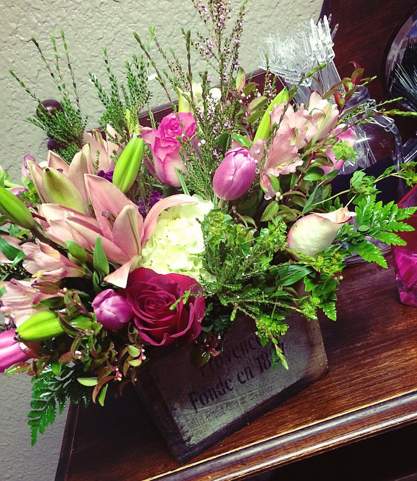 Mixed bouquet of pink lilies, roses, and tulips in a rustic container