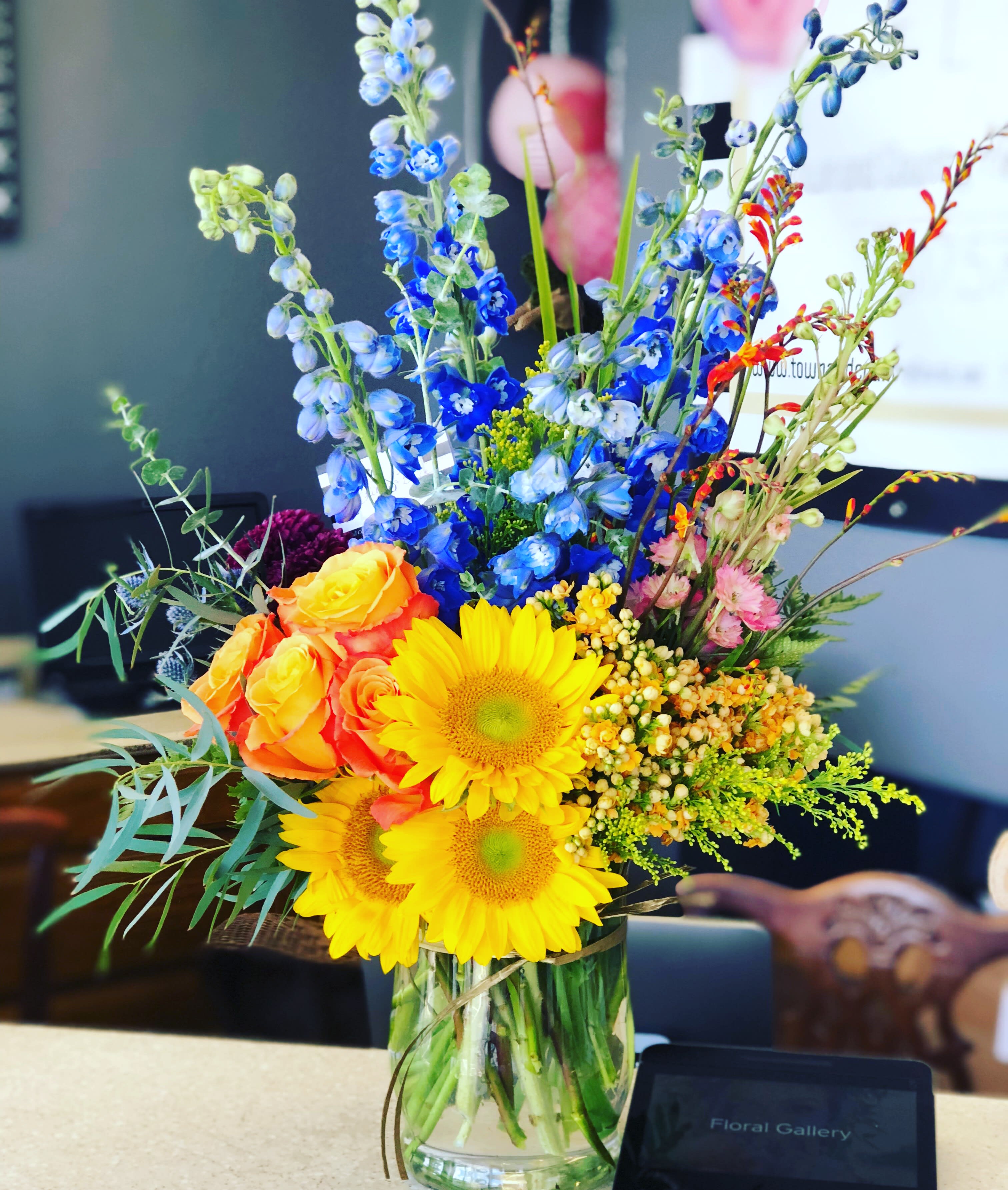 Colorful mixed bouquet in a clear glass vase with sunflowers and roses