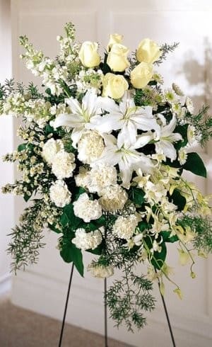 White lilies and pale yellow roses in a standing floral spray