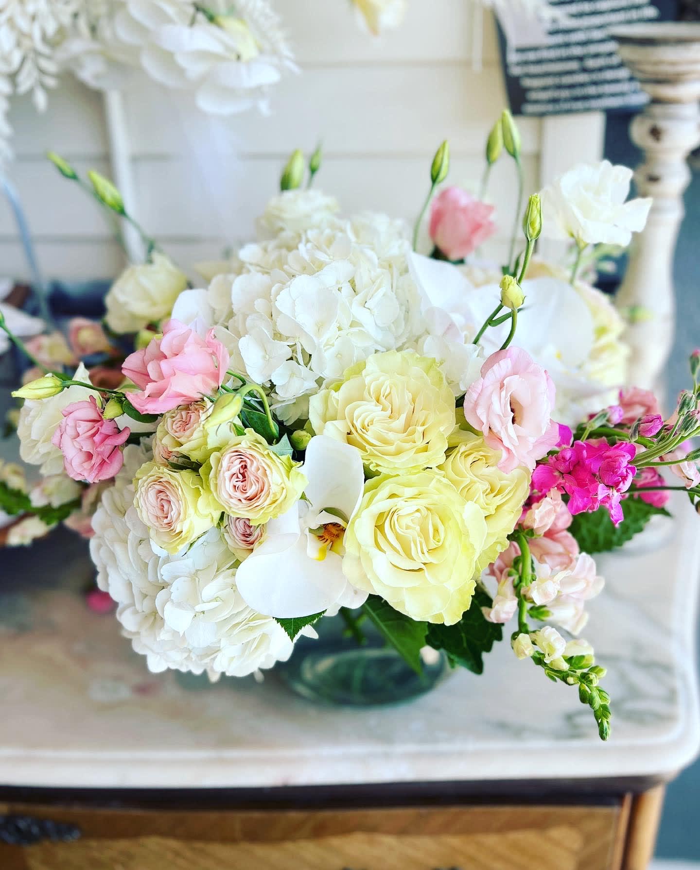 Pastel bouquet of roses, hydrangeas, and white orchids in a glass vase