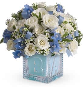 White roses and blue flowers arranged in a glass cube vase