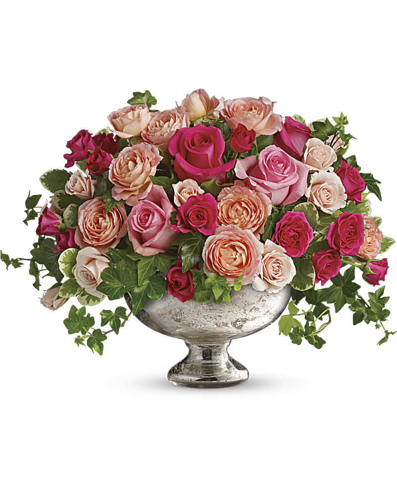 Pink and peach roses arranged in a silver pedestal vase