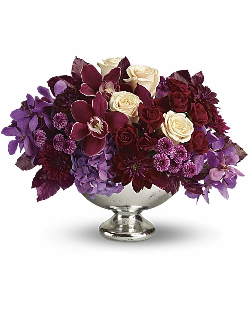 Lush and Lovely - It's elegant, chic, even stunning. But your guests will simply describe it as "Wow!" This luxuriously lush, incredibly stylish arrangement gathers orchids, roses, hydrangea, dahlias and cushion mums into a gorgeous Mercury Glass Bowl. It's sure to make quite an impression as a fall or winter wedding centerpiece - or as a lavish gift delivered to someone truly special. Lush blooms including lavender hydrangea, red cymbidium orchids, purple mokara orchids, crème roses, dark red roses, burgundy dahlias, lavender button mums and purple cushion mums are accented with burgundy copper beech leaves in Teleflora's generous Mercury Glass Bowl.