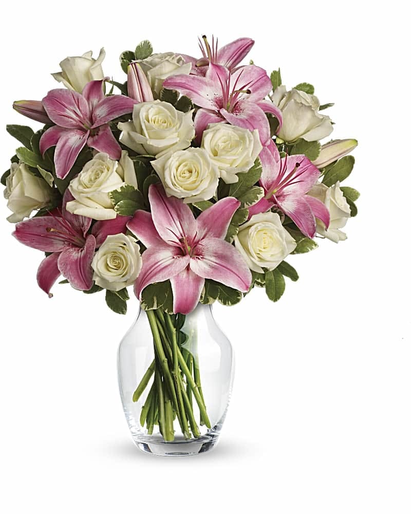 Pink lilies and white roses arranged in a clear glass vase