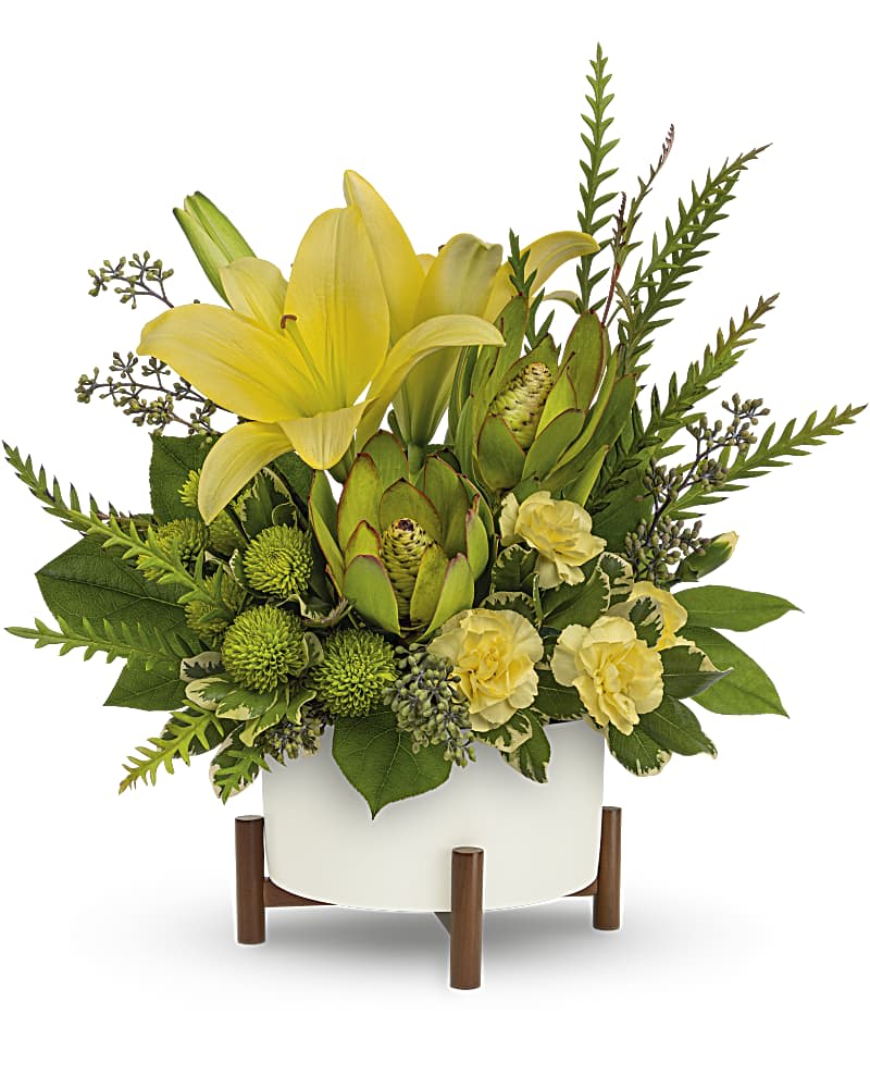 Yellow lilies and green protea in a white planter on wooden legs