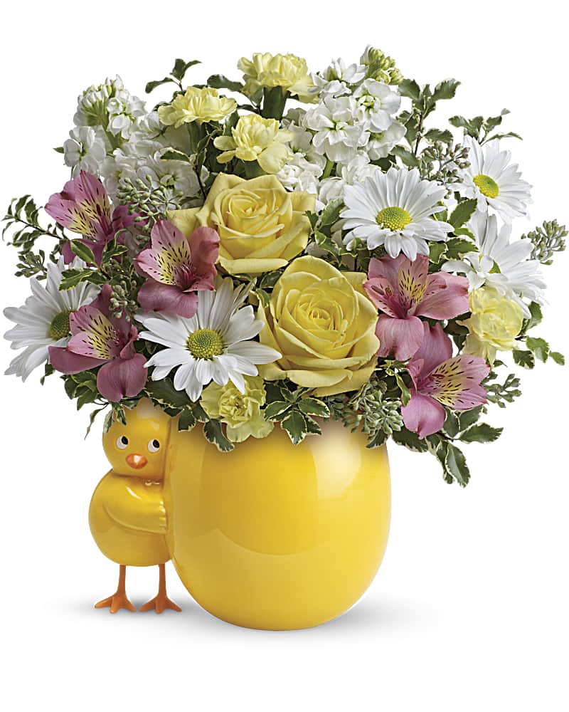 Yellow mug-shaped vase with mixed flowers and a chick figurine