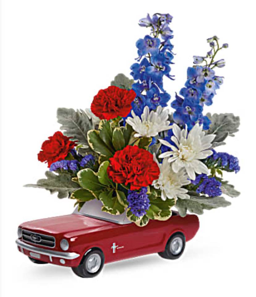 Red toy car topped with red, white, and blue flowers