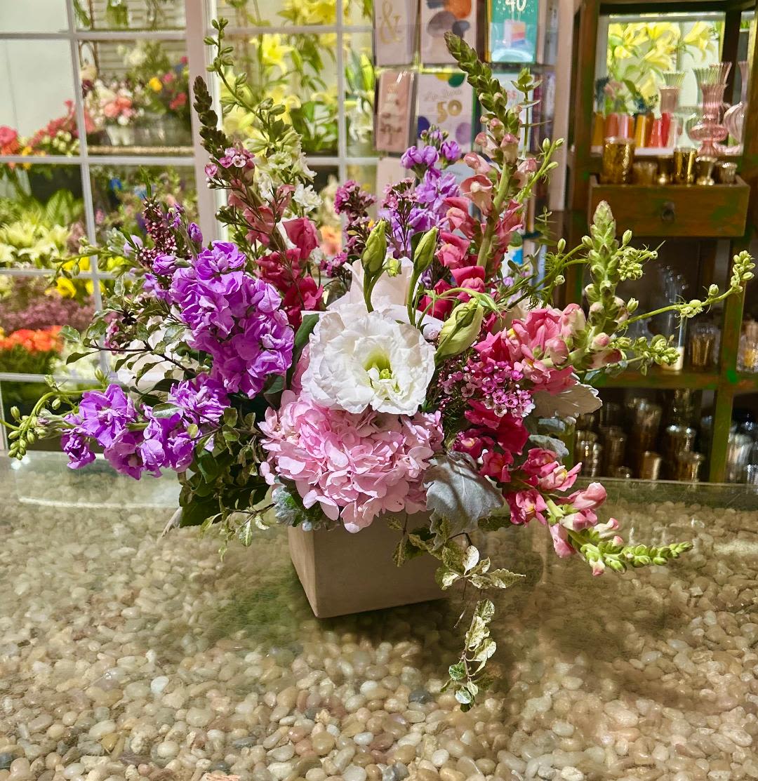 Pink, purple, and white flowers arranged in a square vase