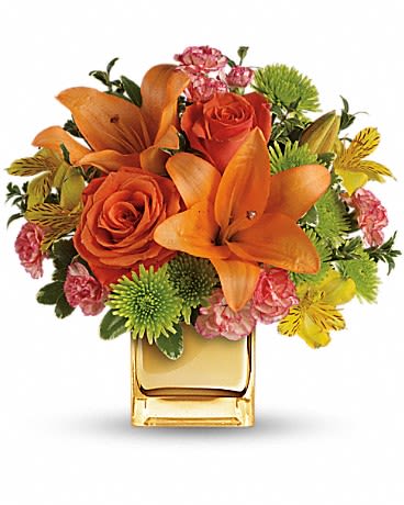 Orange lilies and roses in a square glass vase