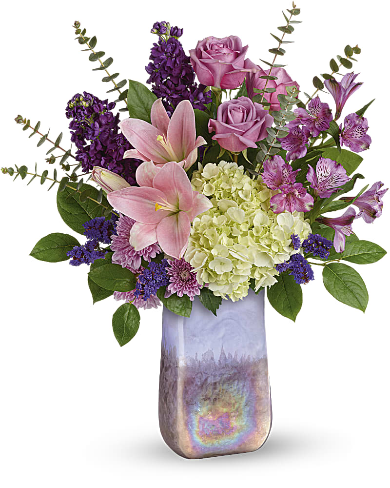 Pink lilies, roses, and purple flowers in a tall iridescent vase