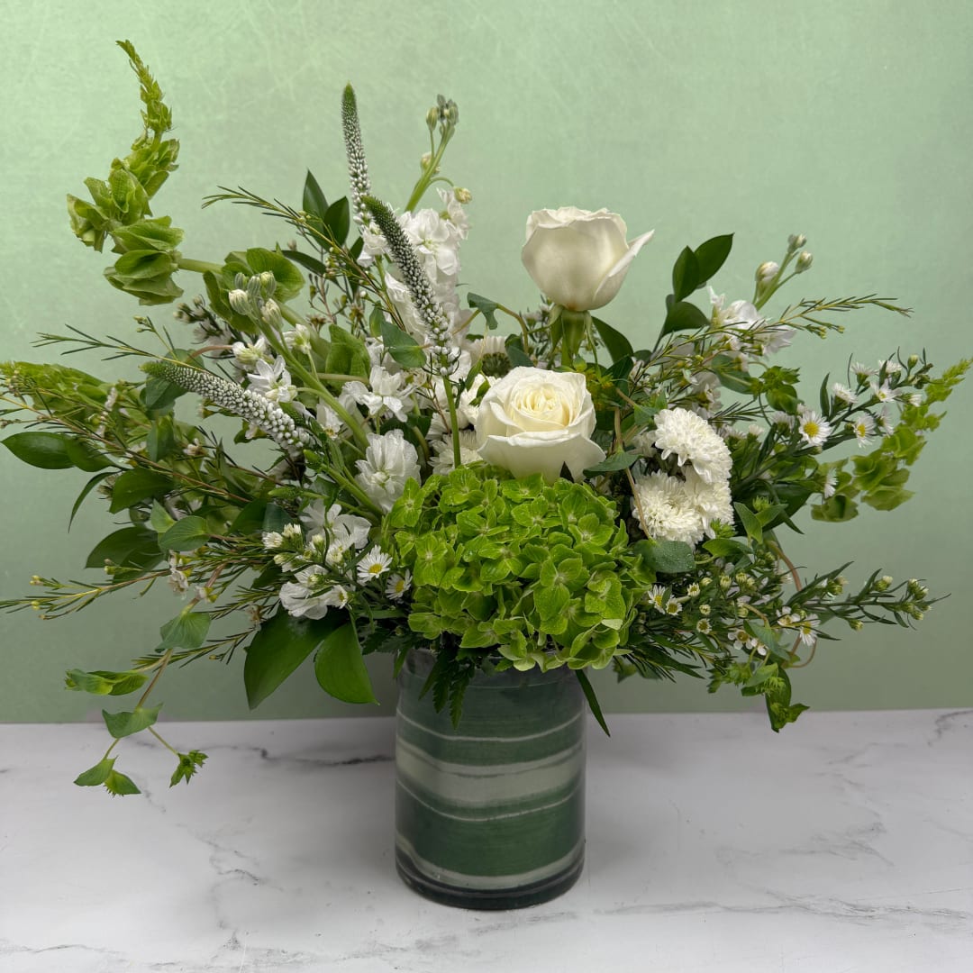 Timeless &amp; Elegant Cylinder - A crisp and elegant mix of white and green blooms designed to feel clean, fresh, and timeless. Our designers create each arrangement using the freshest flowers available for a naturally beautiful, one-of-a-kind design.  Arranged in a taller cylinder vase, this style offers added height and a more elevated presence.  Available in three sizes. For a fuller, more impactful arrangement, we recommend upgrading to Deluxe or Premium.