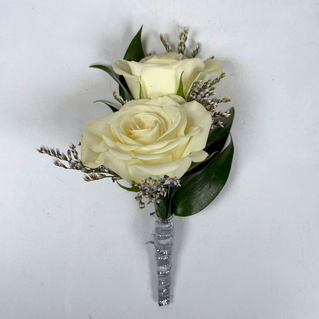 Opal Boutonniere - With Wrap - Two creamy ivory roses are center stage in our Opal Boutonniere, a compact, formal boutonniere that looks great with any outfit, perfect for prom night. Small limonium filler blooms surround the roses, and dark green leaves tuck in beneath to give contrast and depth, so the person wearing it will look polished and truly cared for.  This version of the design features the shimmering white sheer ribbon pictured, and a boutonniere pin is included so it sits neatly on a suit or jacket. If you want to change the color of either the ribbon wrap or add dazzling sparkle accents to your boutonniere, check out our add-ons and pick your desired color.