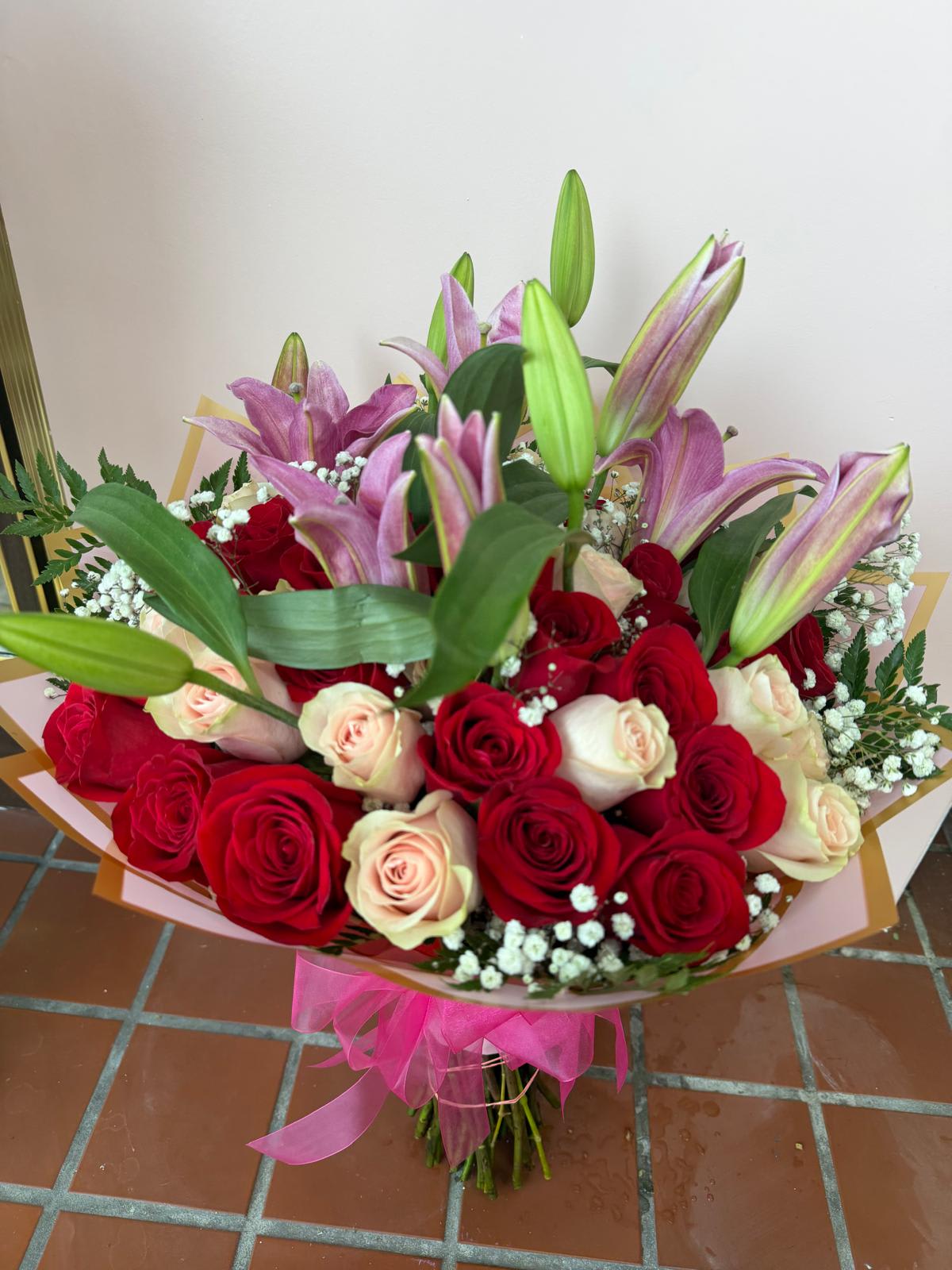 Bouquet of red and blush roses with pink lilies and baby's breath