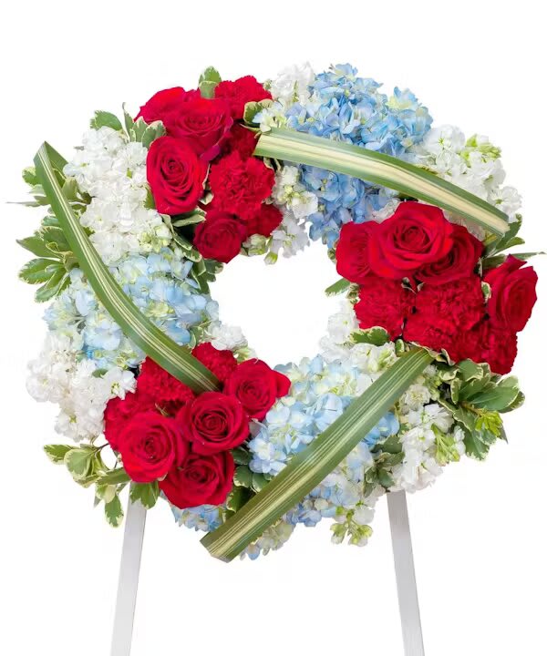 Heart-shaped floral wreath with red roses, blue hydrangeas, and white flowers
