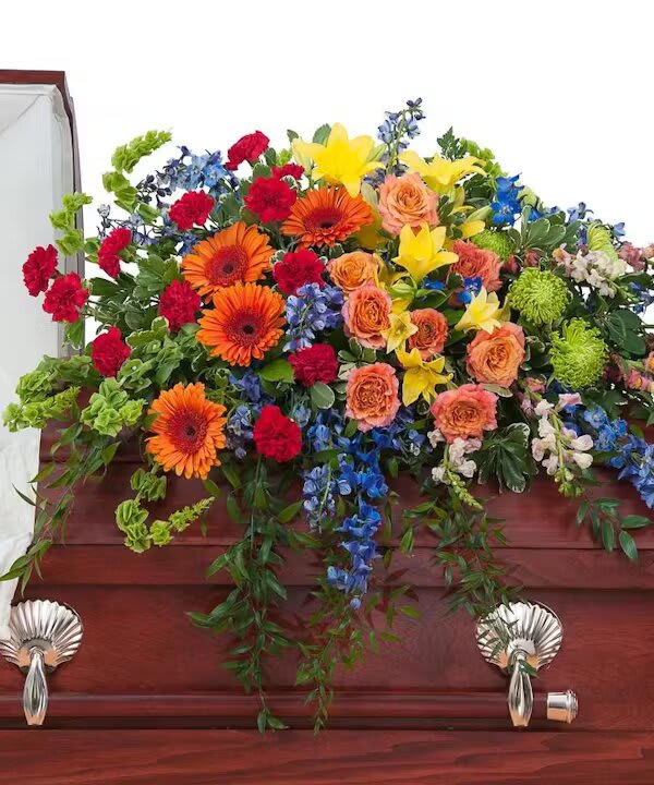 TREASURED CELEBRATION CASKET SPRAY - A combination of bright color blooms to celebrate the life of your loved one.  