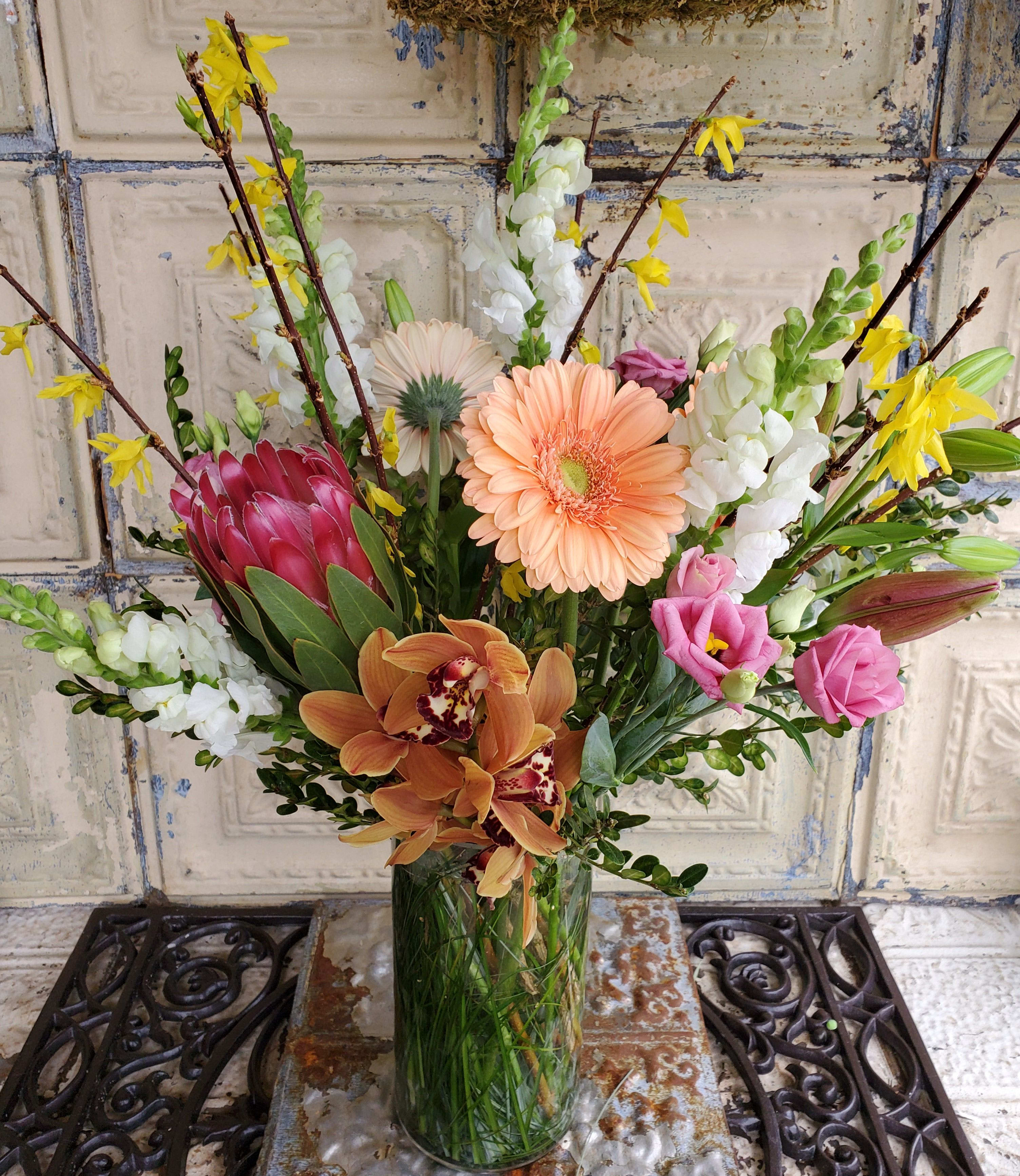 Mixed bouquet in a clear glass vase with pink, peach, white, and yellow blooms