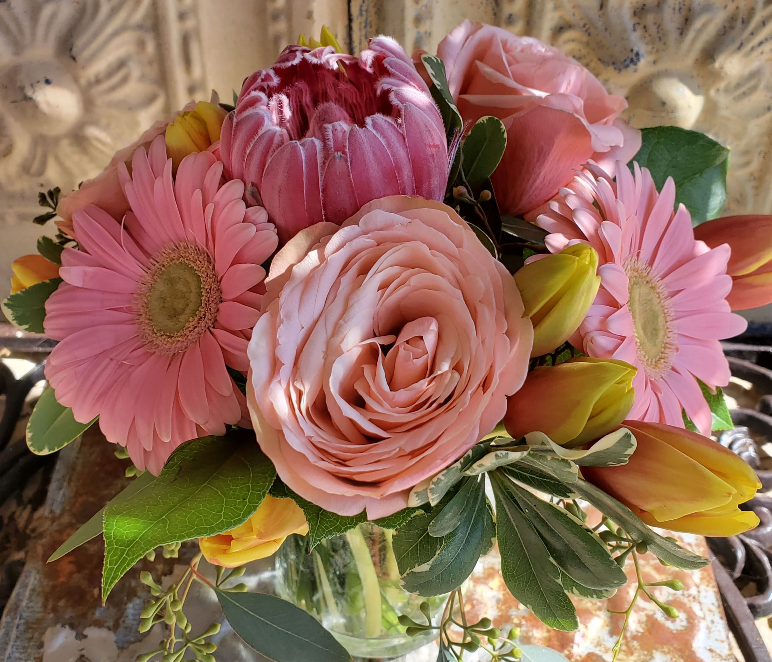 Pink mixed flower bouquet with roses, gerbera daisies, and tulips in a glass vase