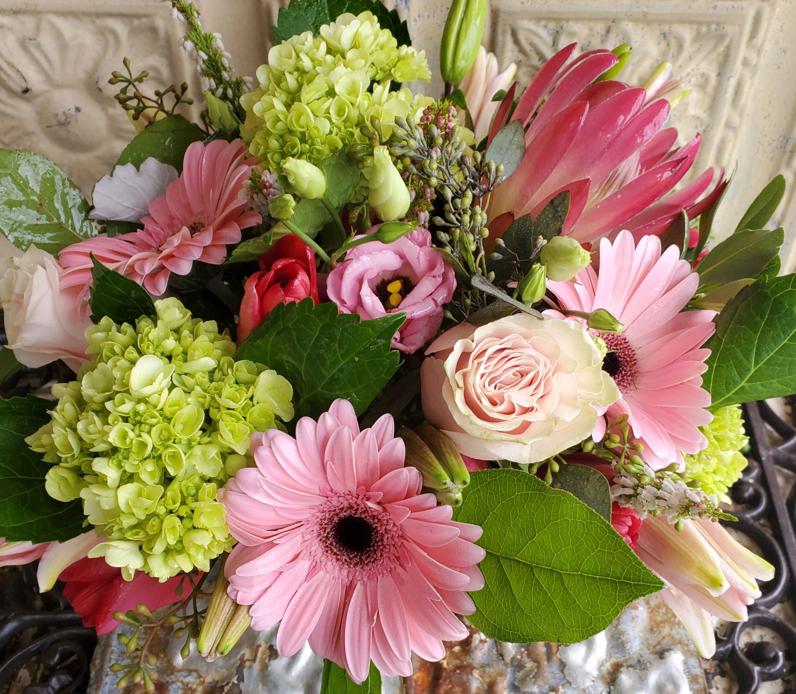 Pink gerbera daisies and roses with green hydrangeas in a bouquet
