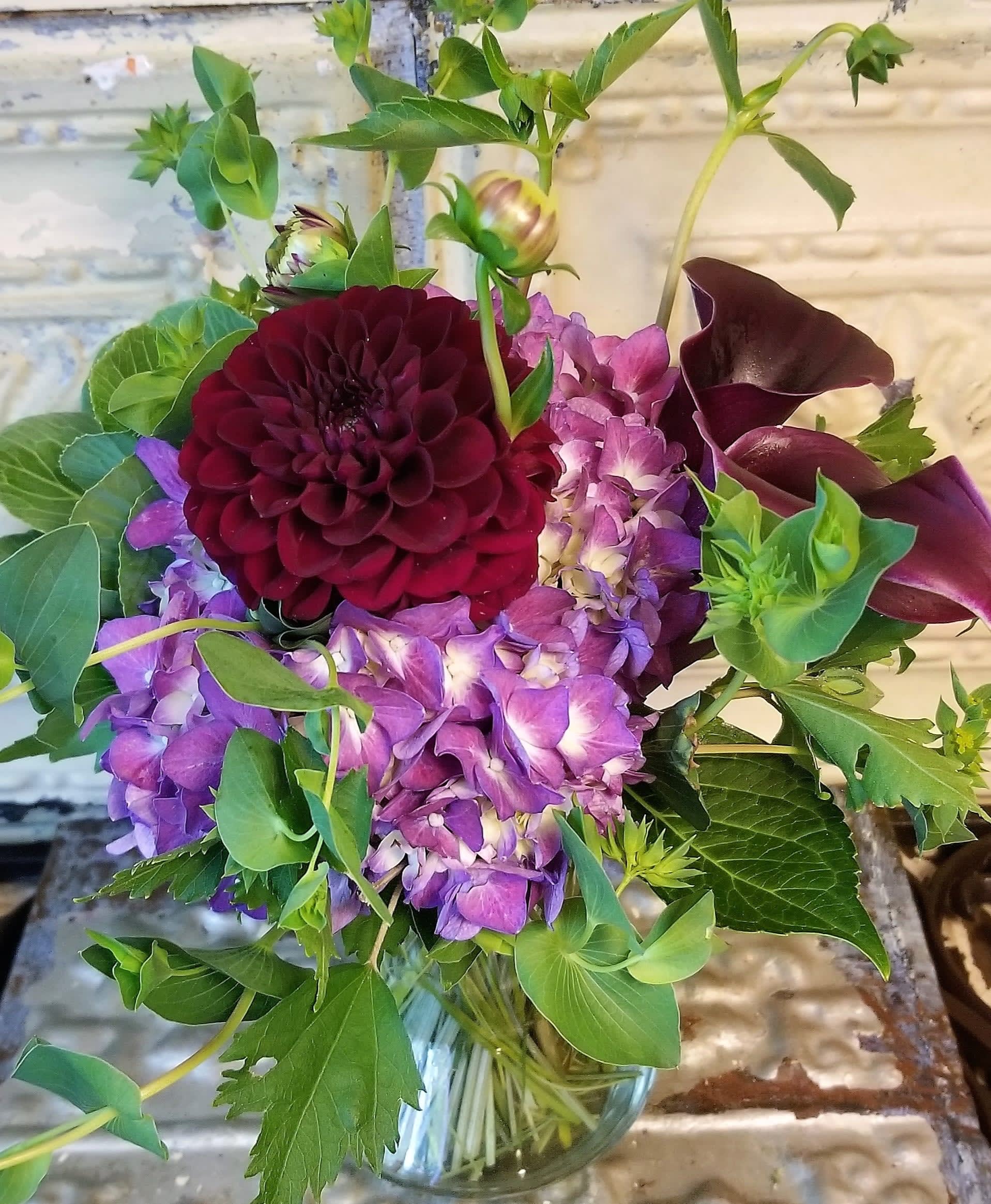 Bouquet of purple flowers with dark burgundy blooms in a glass vase
