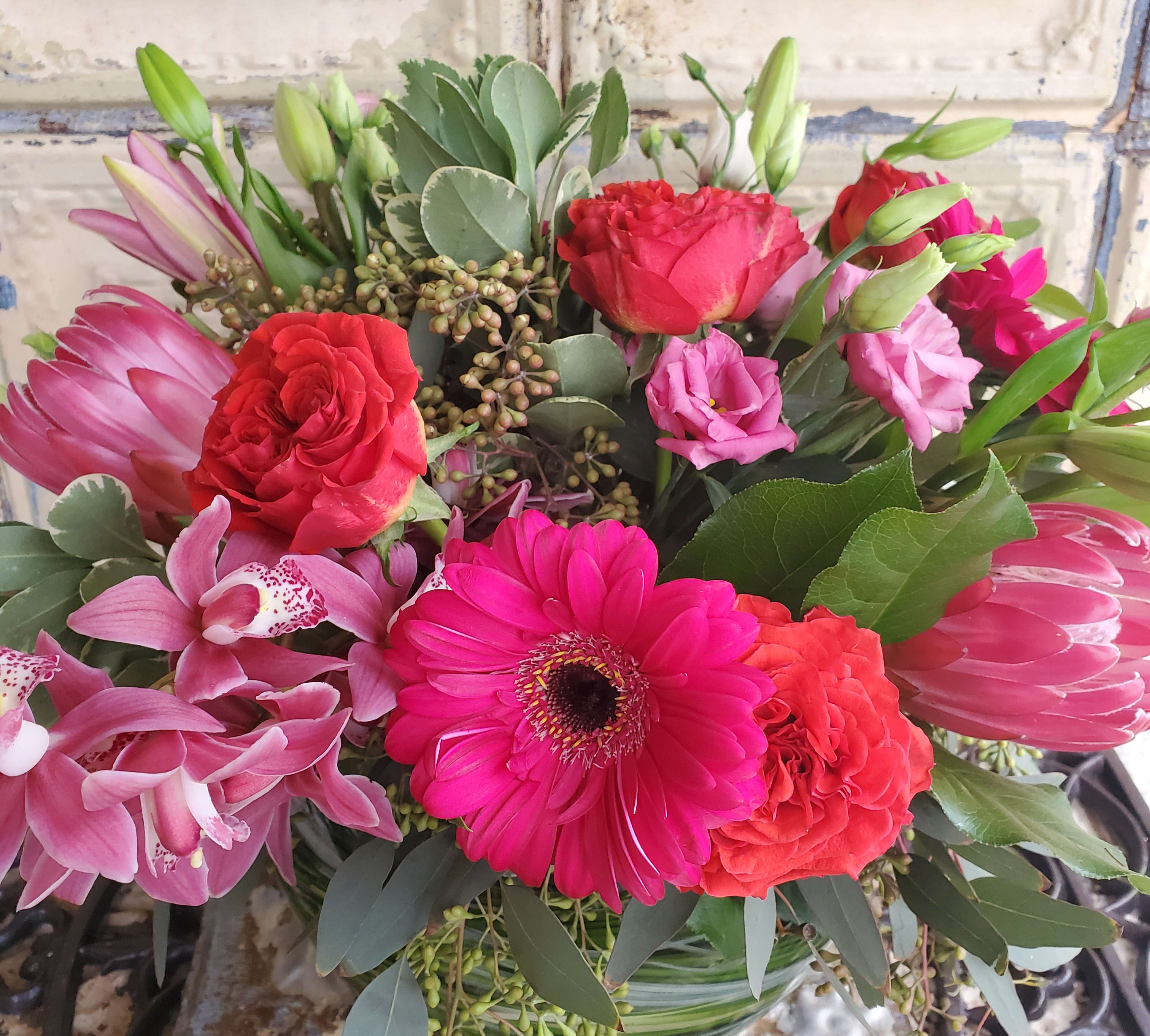 Mixed bouquet with pink orchids, red roses, and a bright pink gerbera daisy