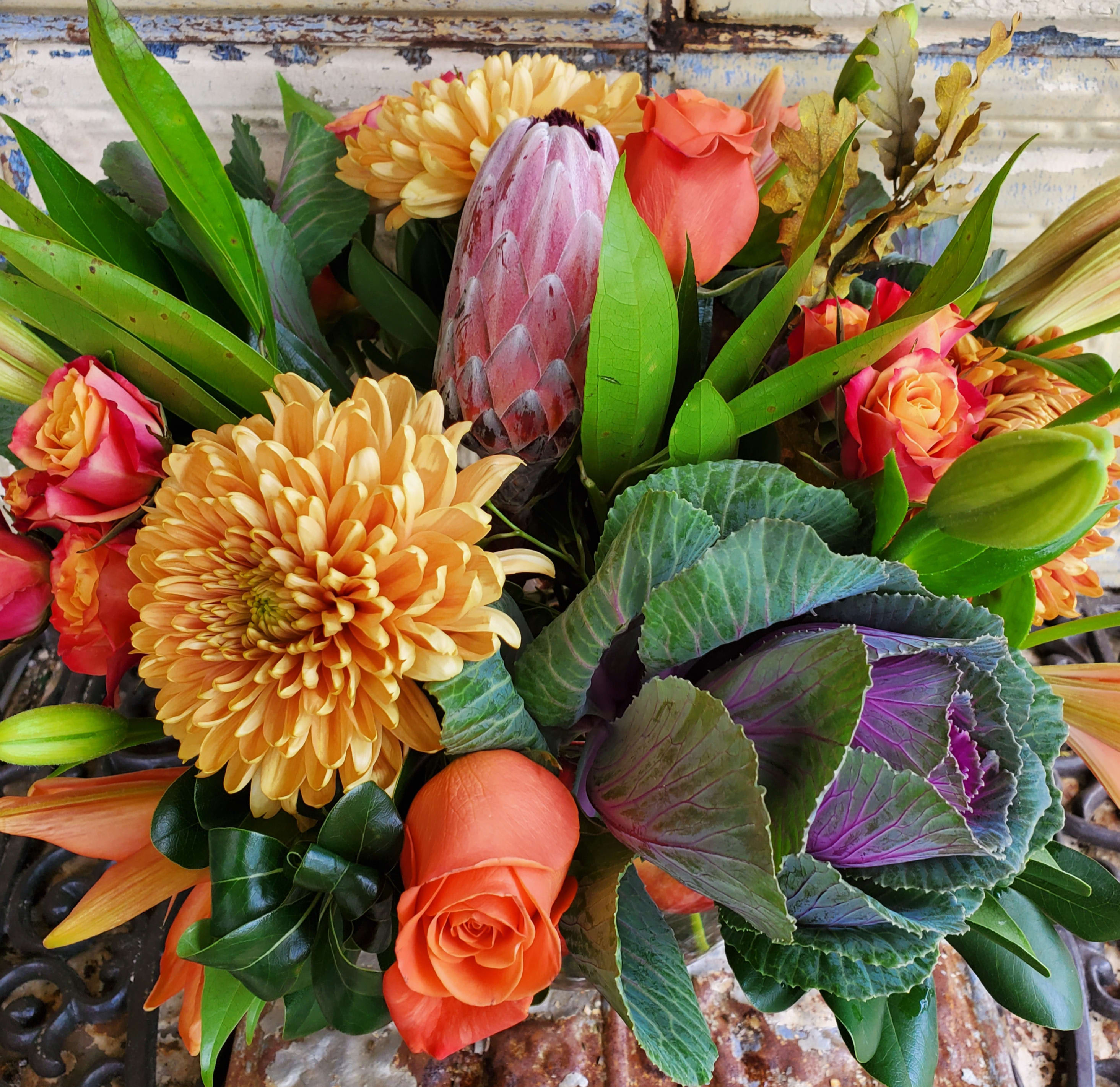 Bouquet of orange roses, yellow chrysanthemums, and a pink protea
