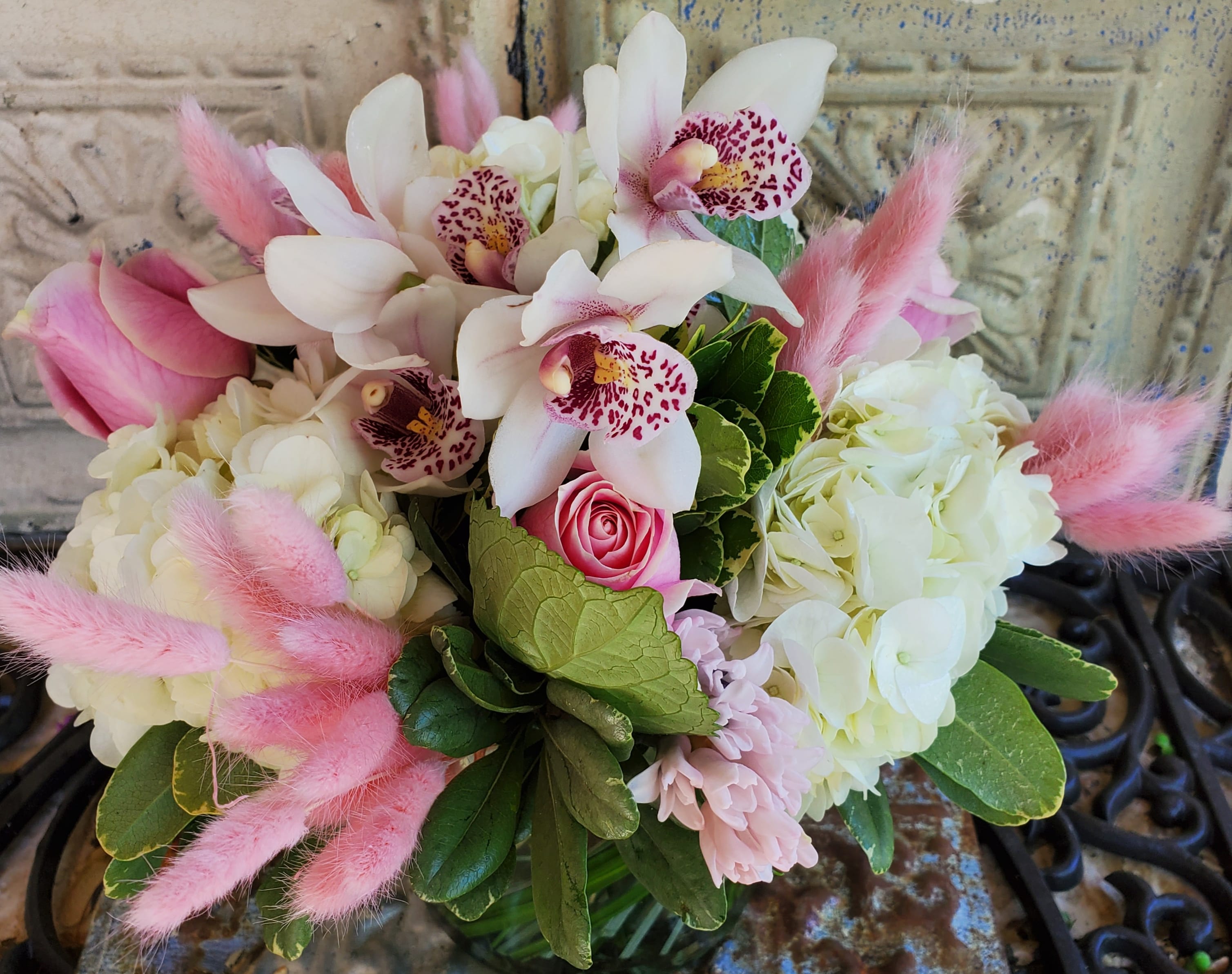 Pink and white bouquet with orchids, roses, hydrangeas, and fluffy pink accents