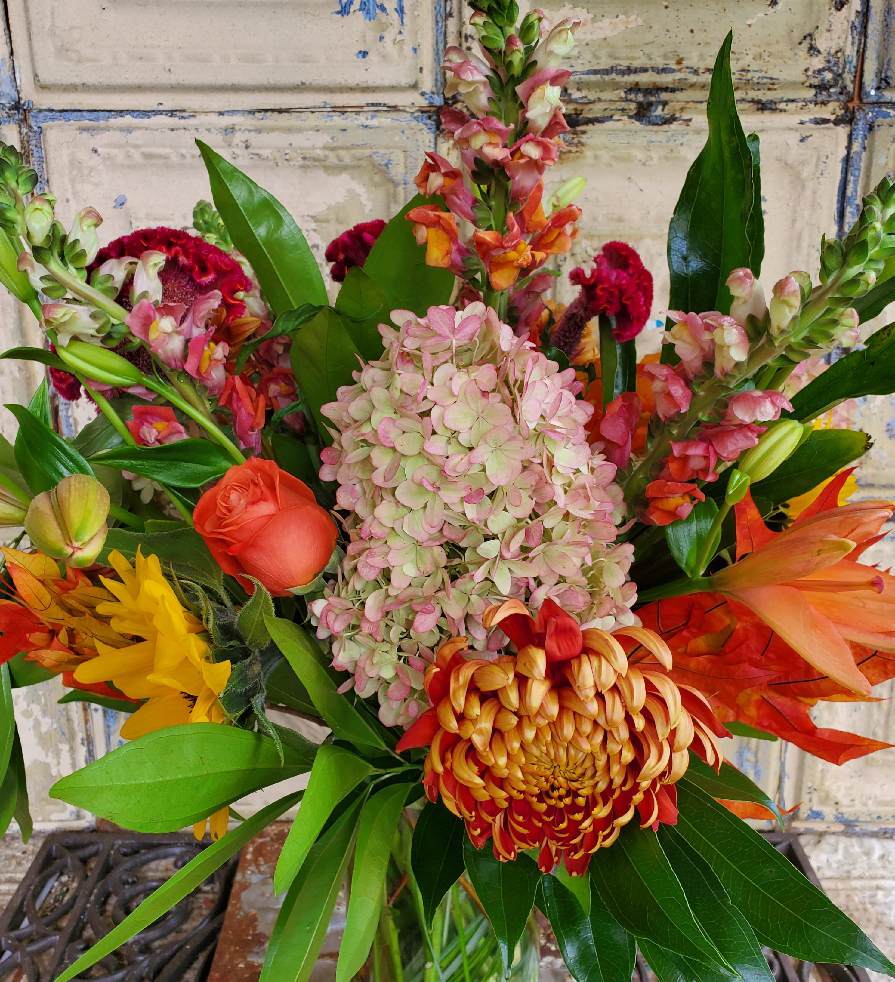 Mixed bouquet with pink hydrangea, orange roses, and tropical blooms