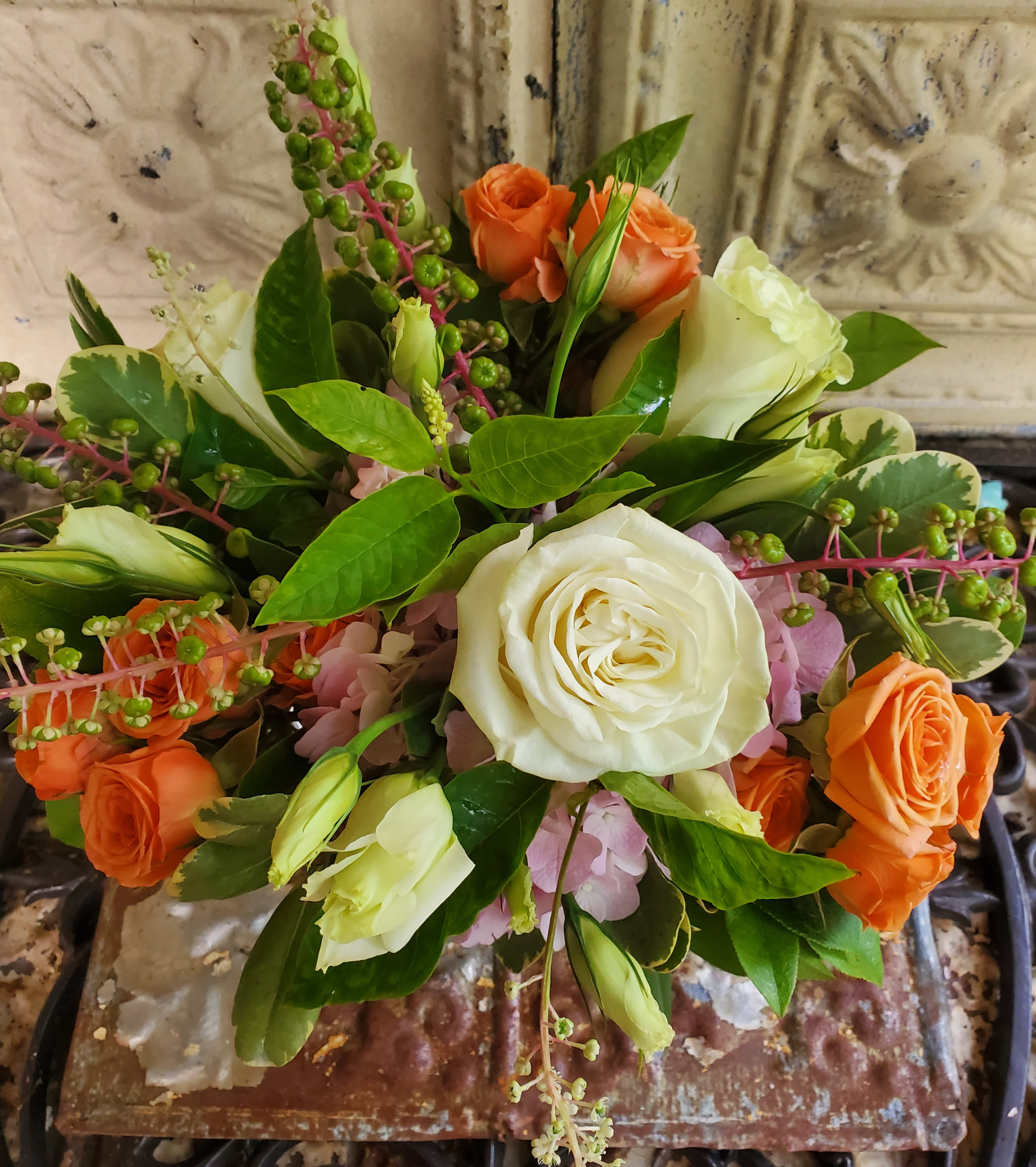 Bouquet of white and orange roses with green berries and pink flowers