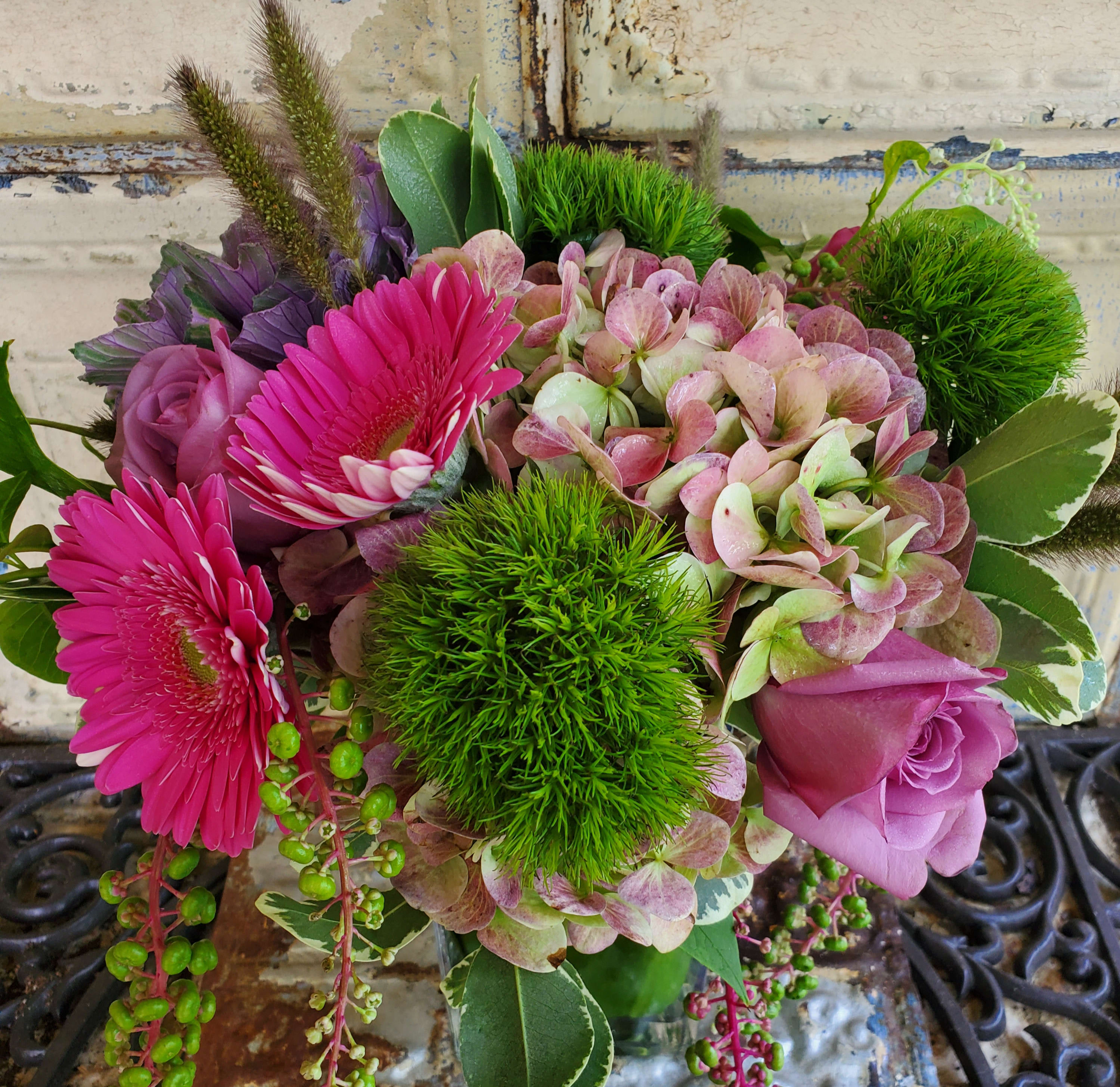 Pink gerberas and roses with hydrangea and green pom-pom blooms in a vase