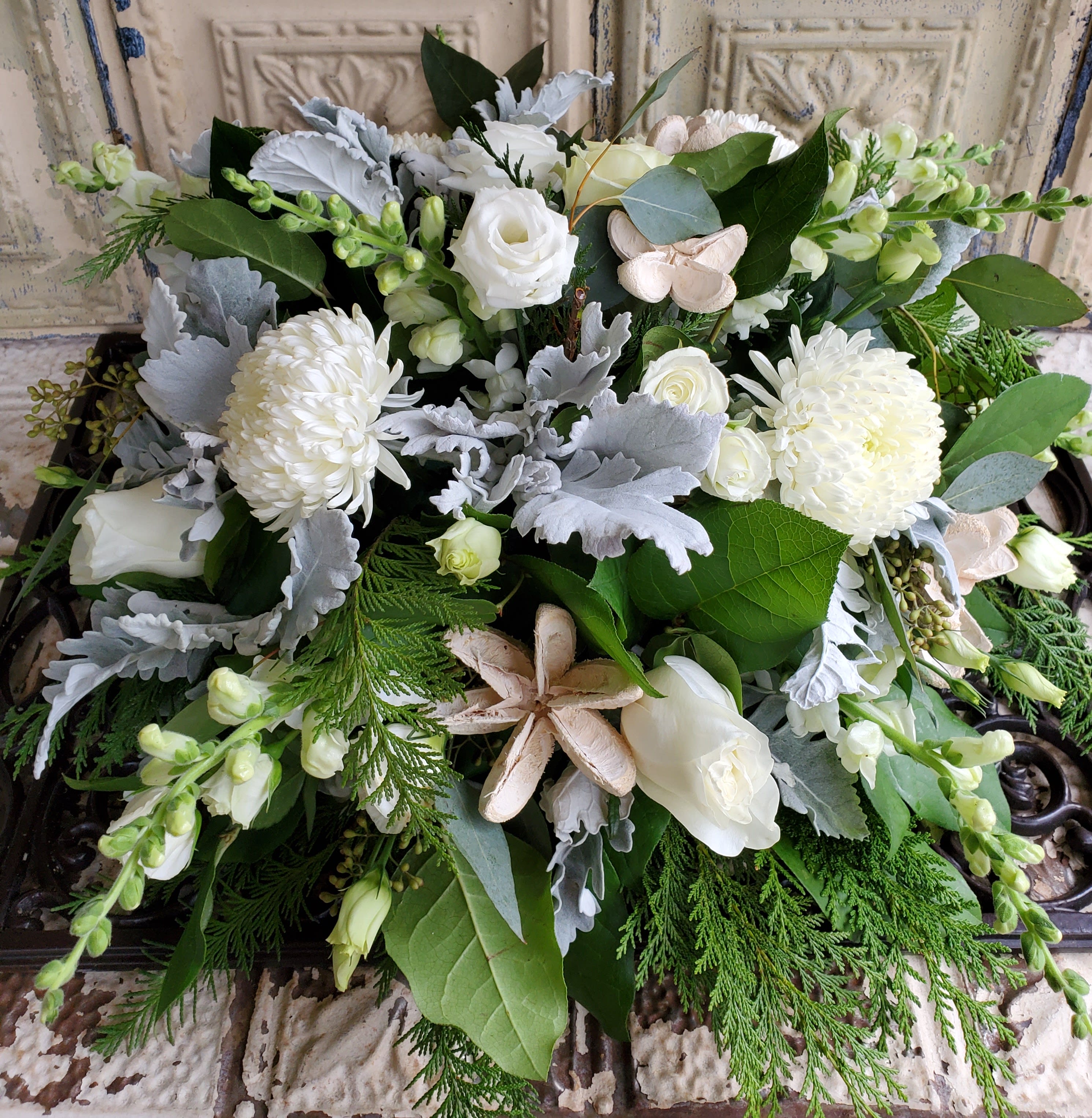 White floral arrangement with roses, mums, and greenery