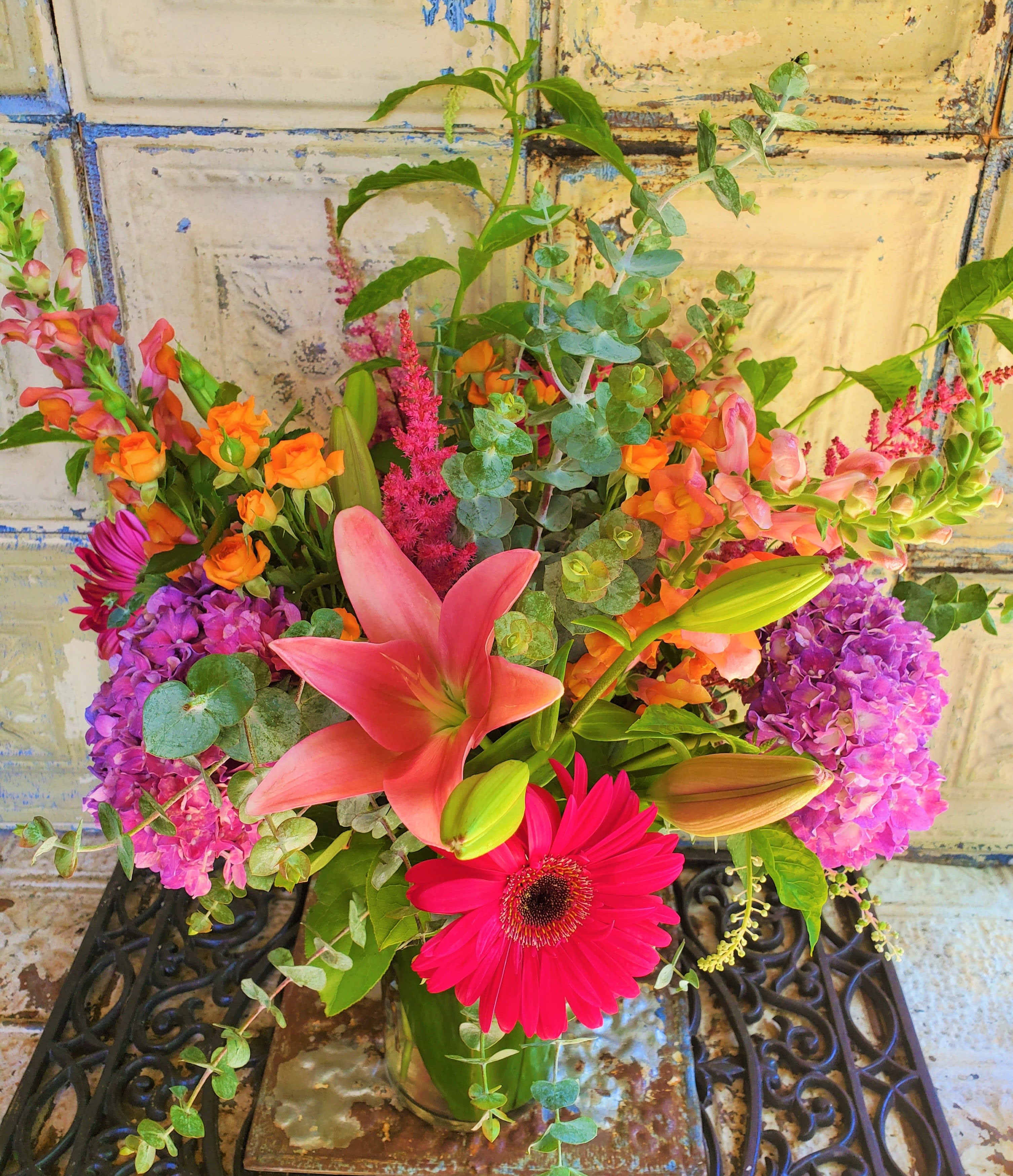 Mixed bouquet with pink lilies, gerbera daisies, and purple hydrangeas in a glass vase