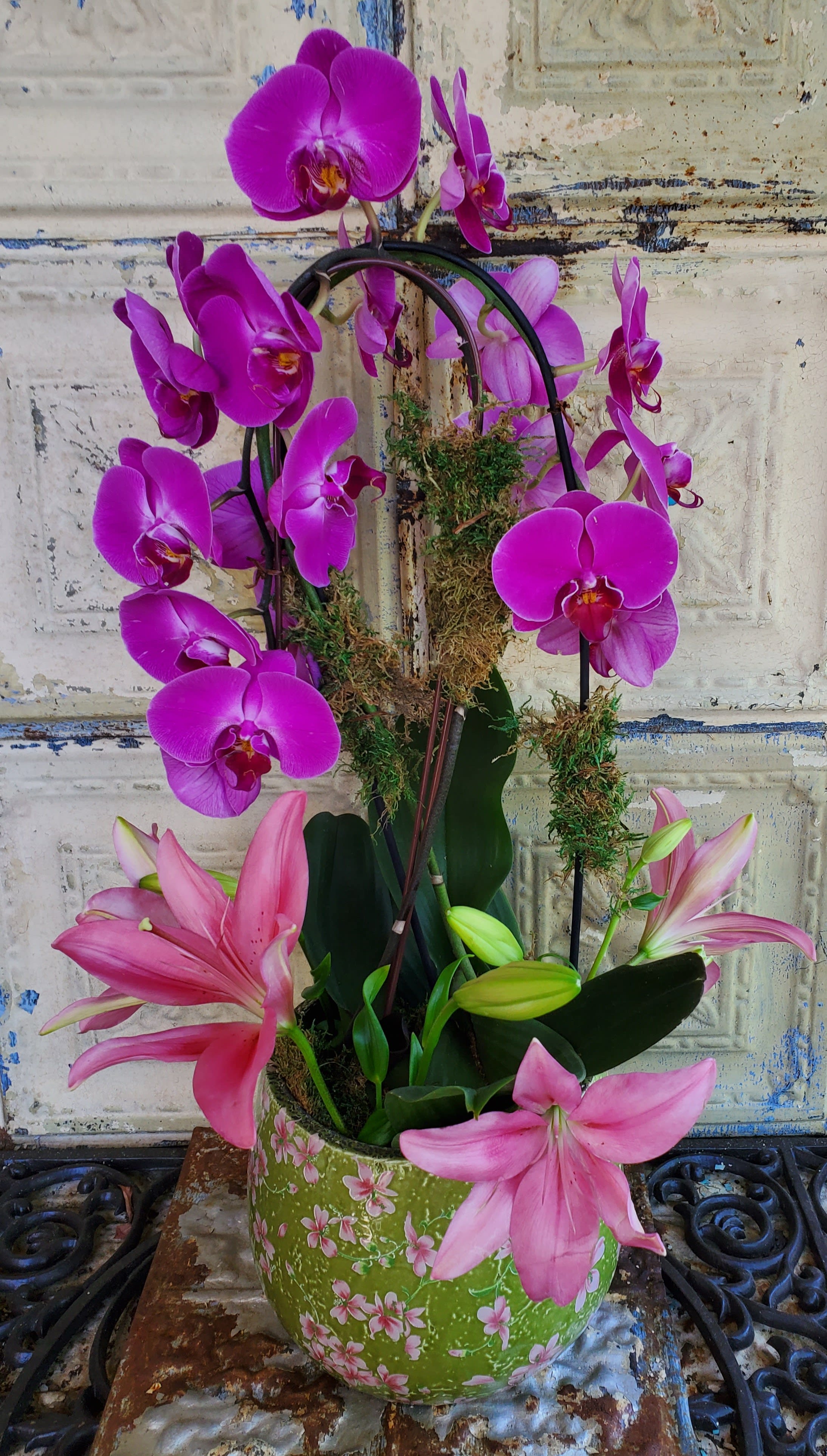 Pink orchids and lilies arranged in a floral pot