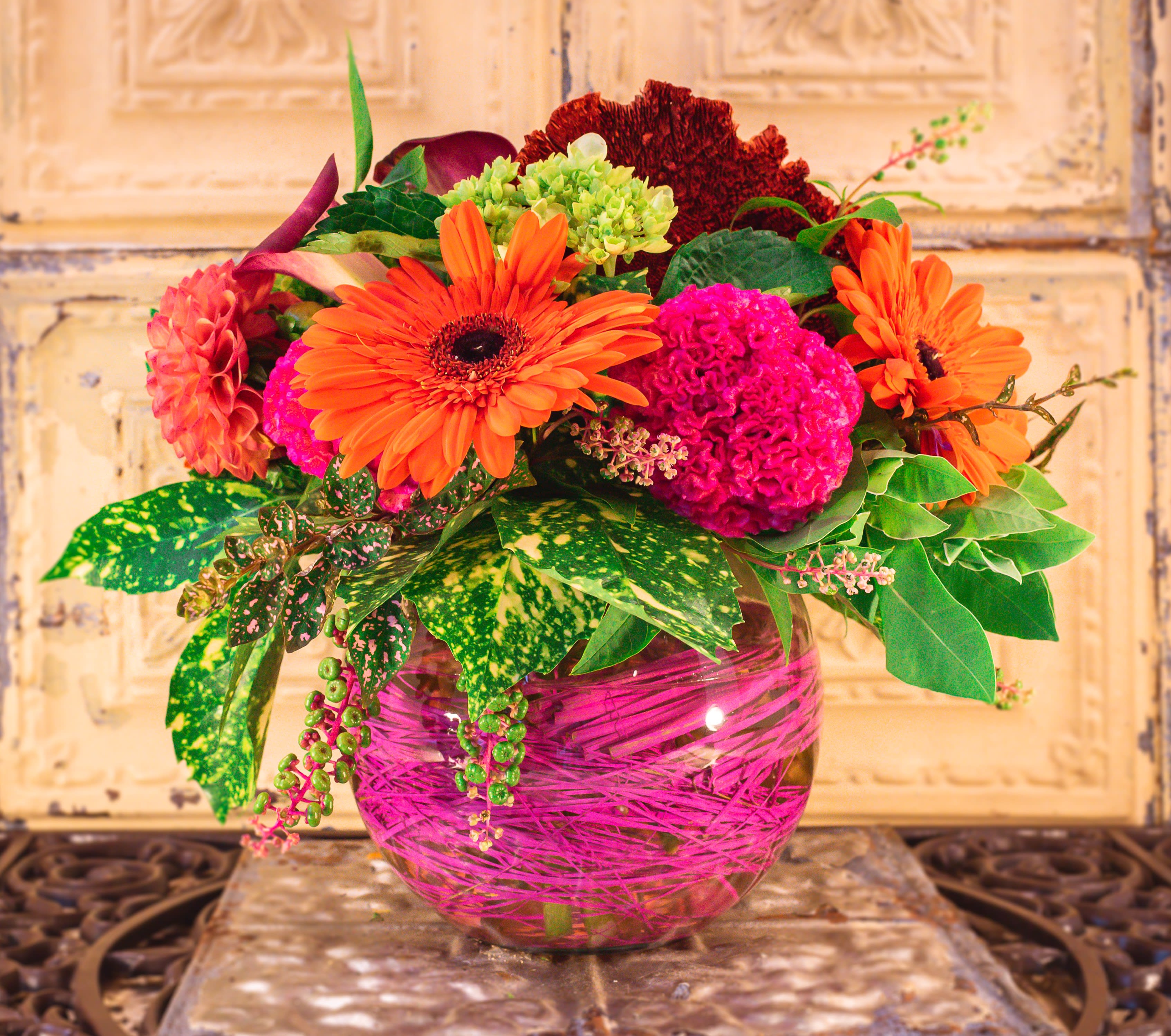 Bright mixed flower arrangement in a pink glass vase