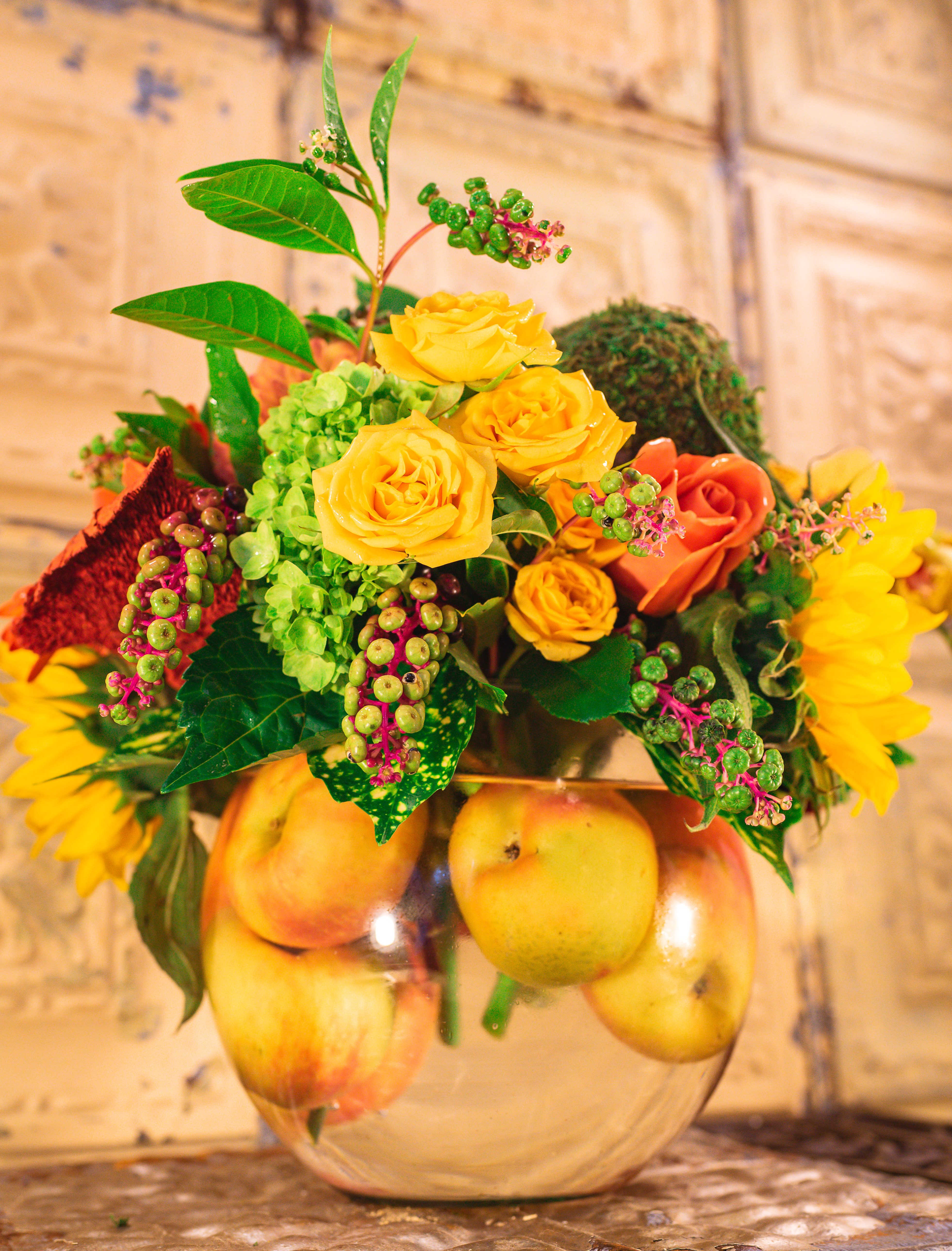 Yellow and orange roses in a glass bowl with apples