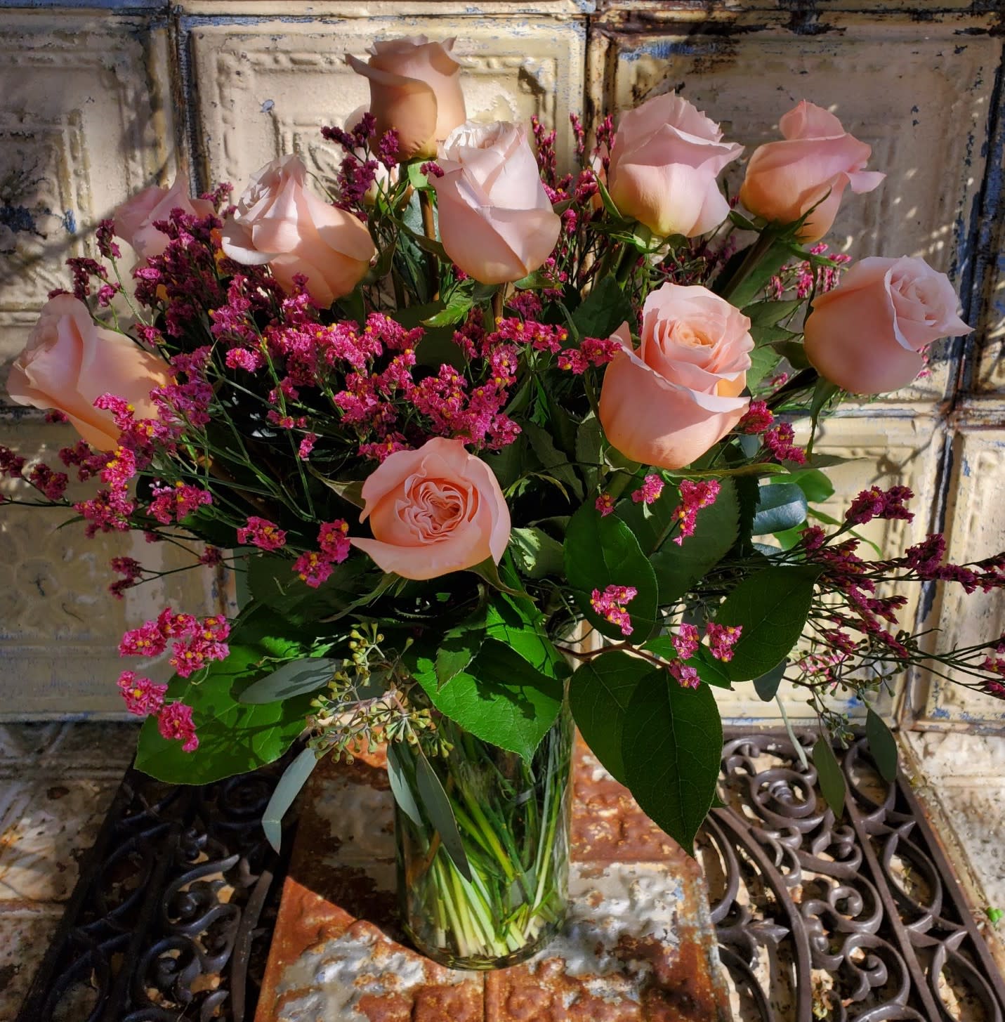 Peach roses in a clear glass vase with pink filler flowers