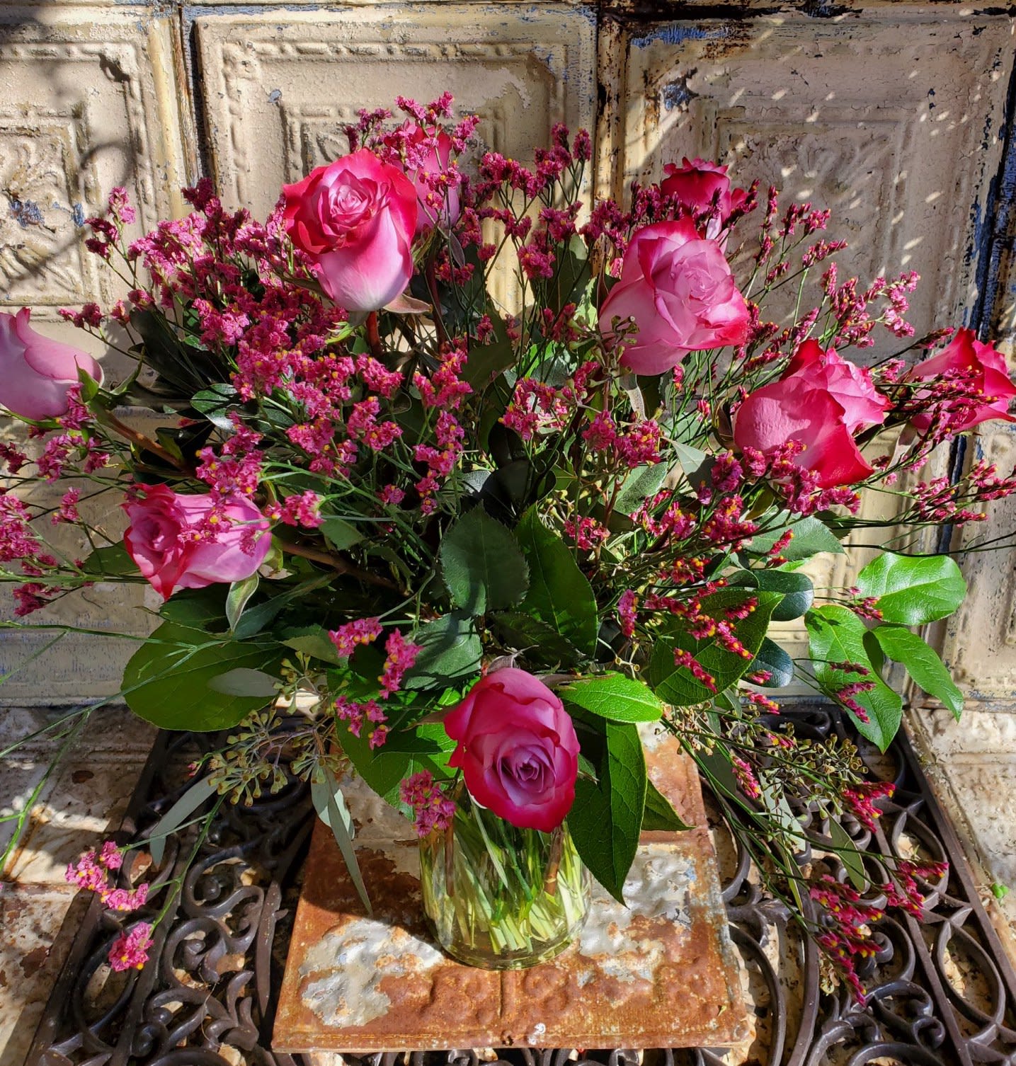 Pink roses in a clear glass vase with small pink filler flowers
