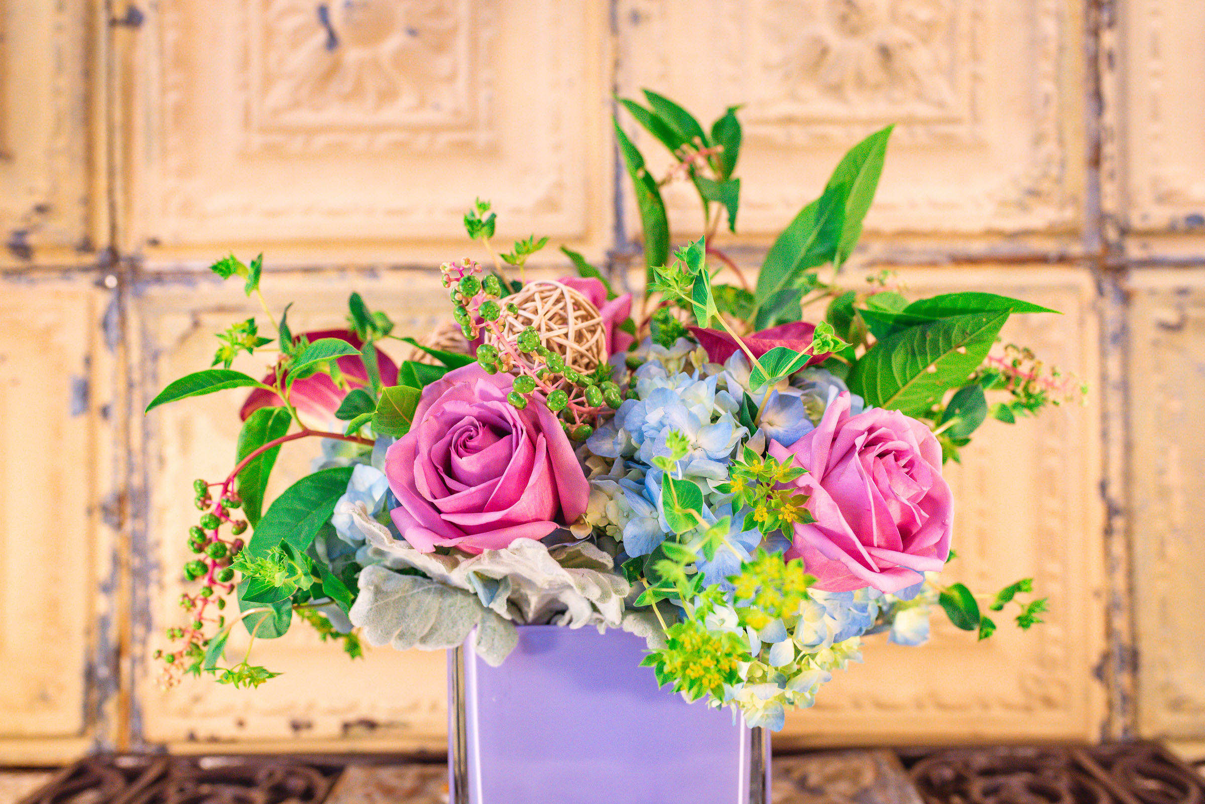 Pink roses and blue hydrangeas in a lavender vase