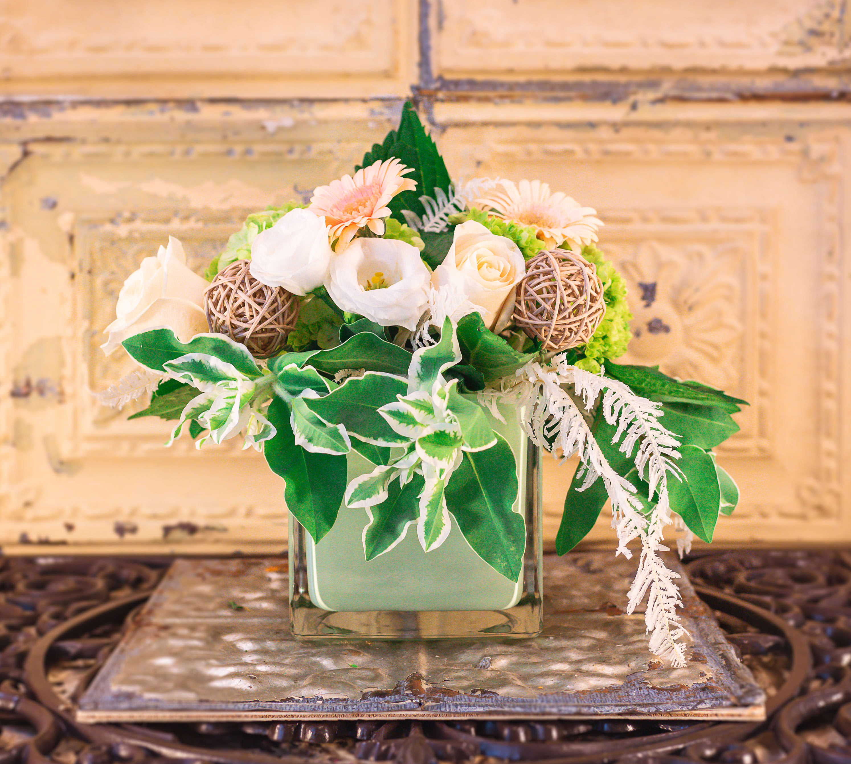 Floral arrangement in a square glass vase with white and peach blooms