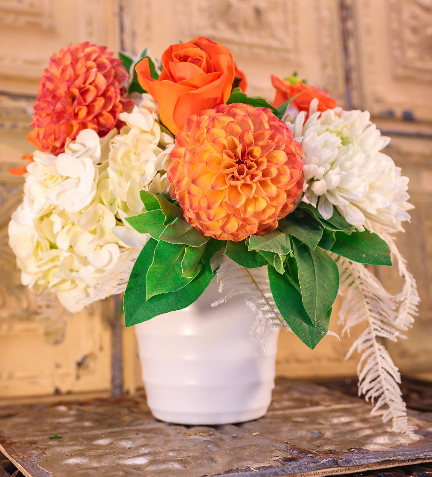 Orange and white floral arrangement in a white pot
