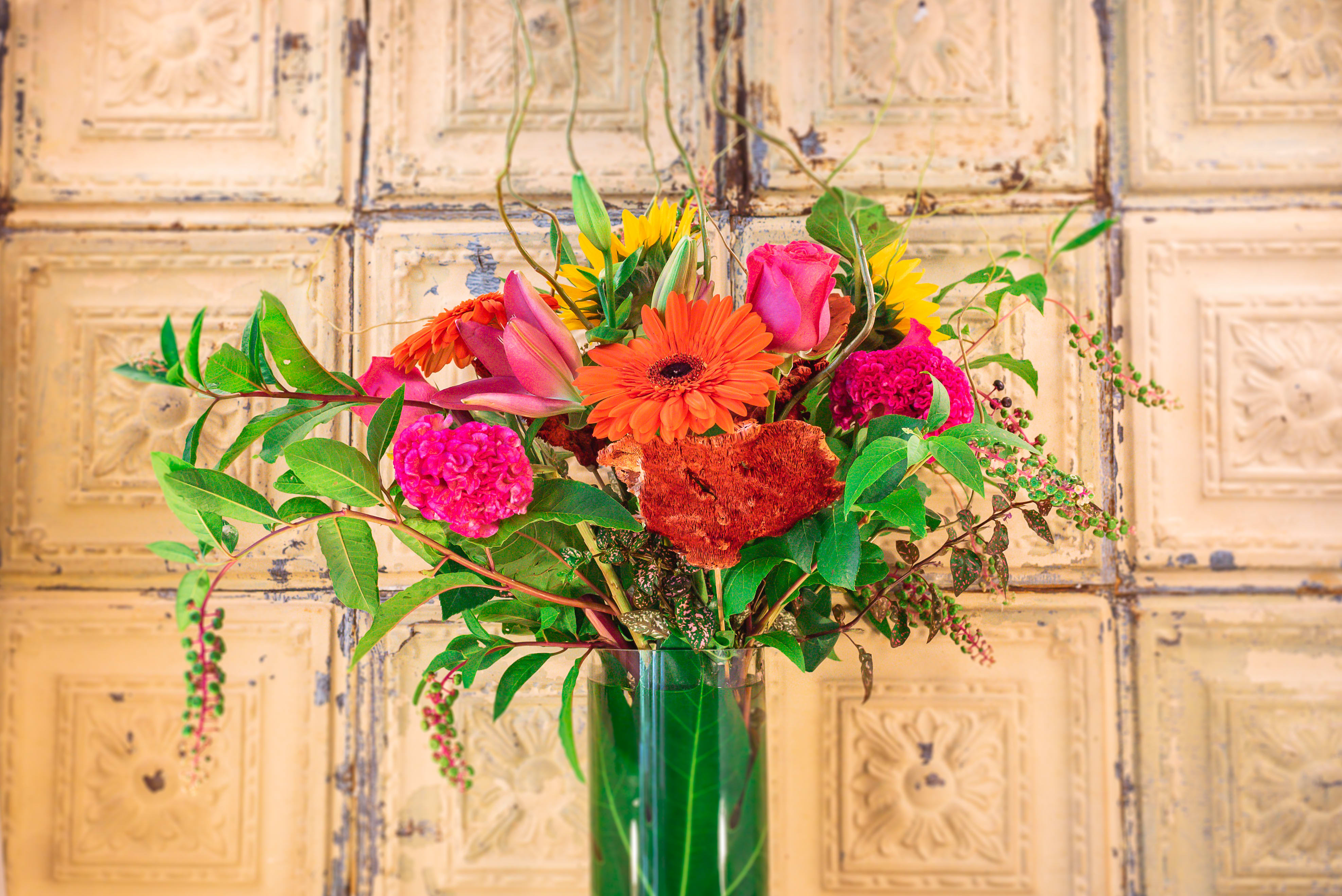Bright mixed bouquet in a tall glass vase with pink, orange, and yellow blooms