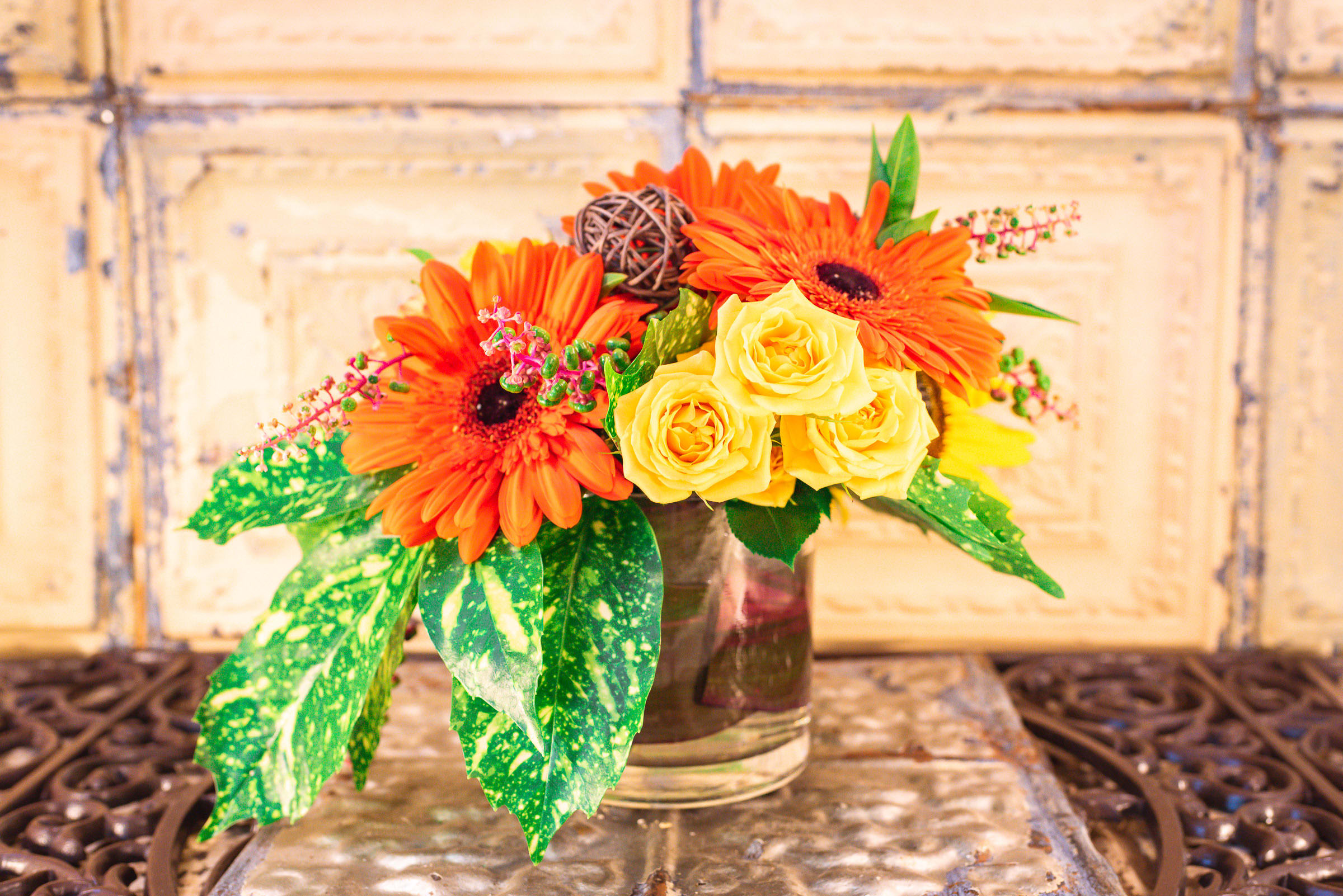 Orange gerbera daisies and yellow roses in a glass vase