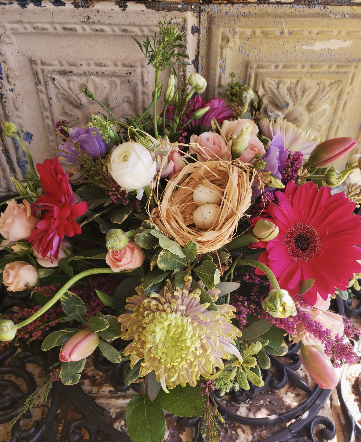 Mixed bouquet with pink gerberas, roses, and a small nest with eggs