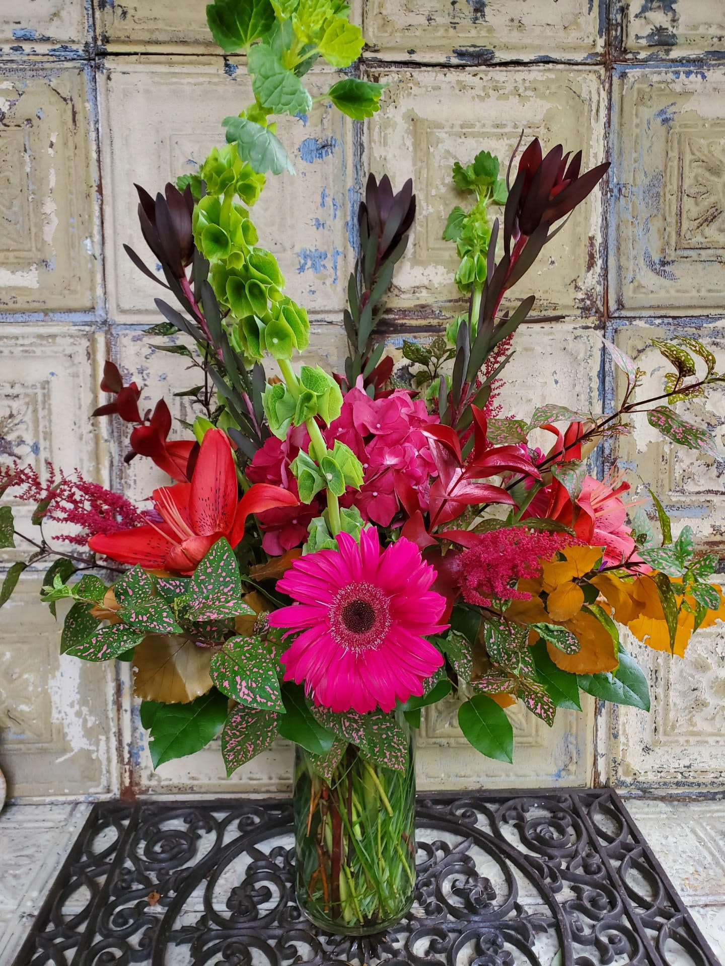 Bright mixed bouquet in a clear glass vase with pink and red blooms