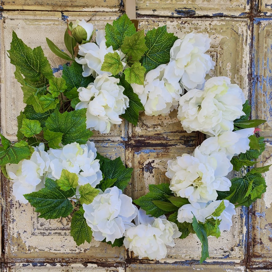 White hydrangea wreath with green leaves on a rustic background