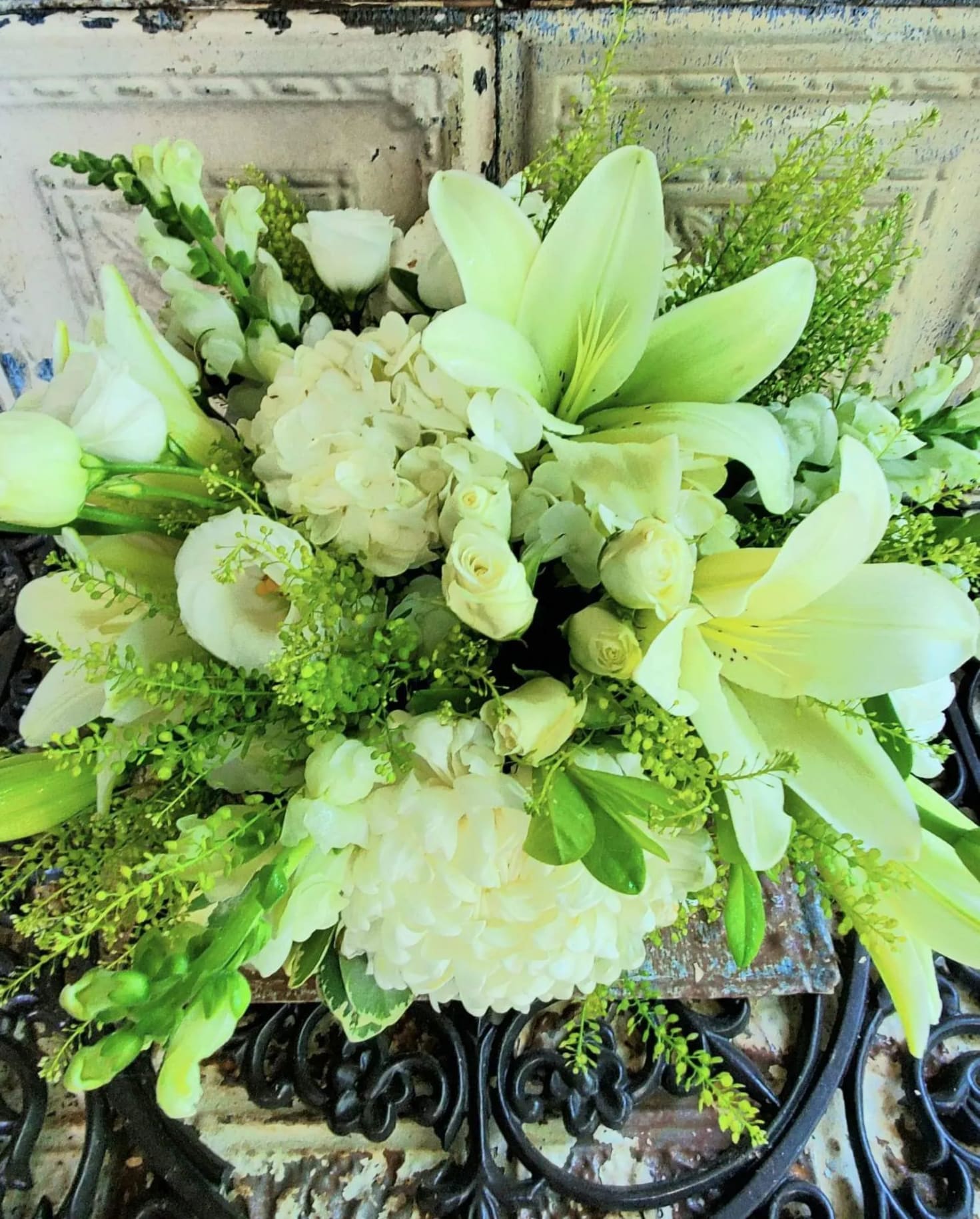 White lilies and roses arranged with hydrangeas and greenery