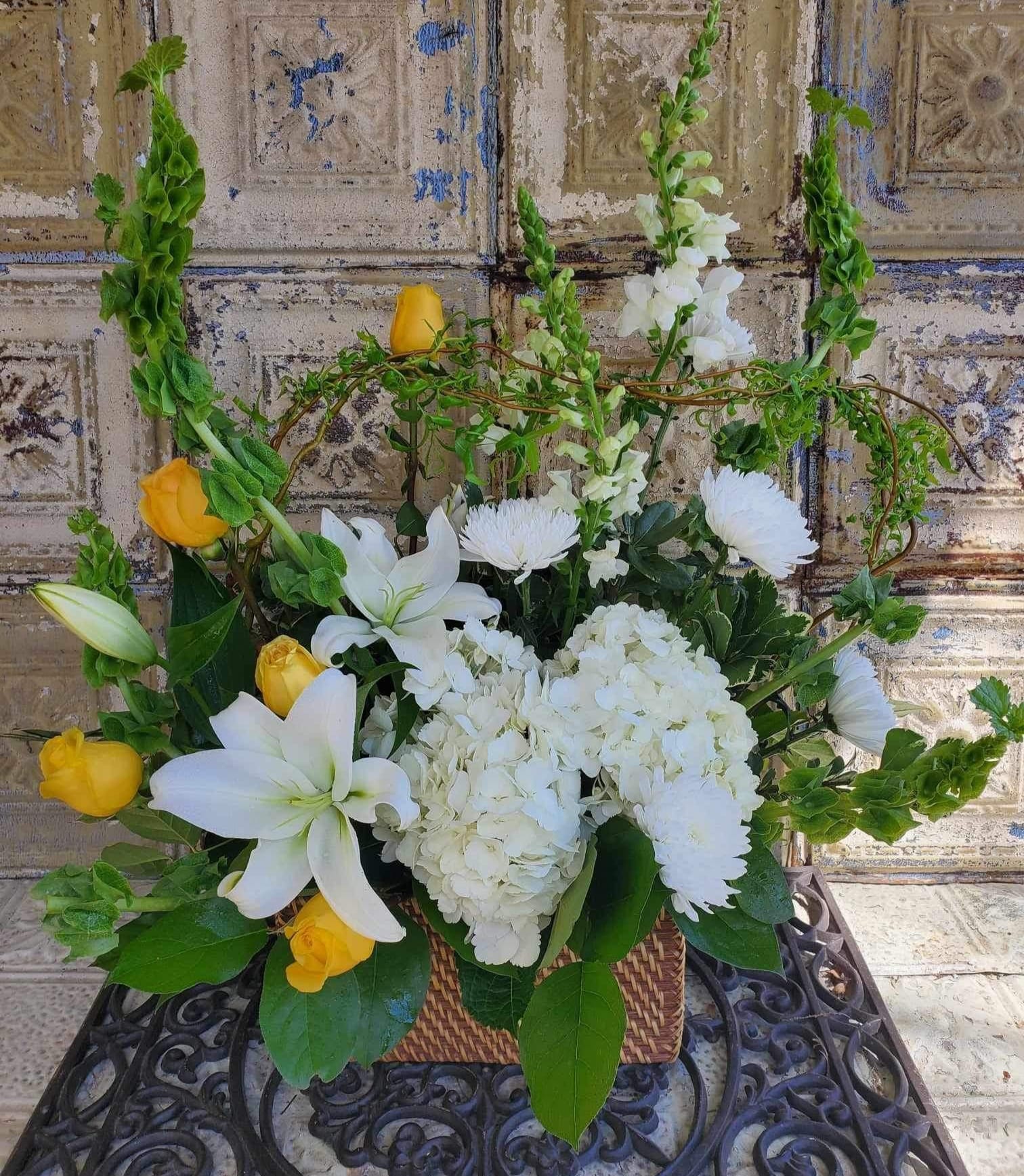 White lilies and yellow roses arranged in a wicker basket
